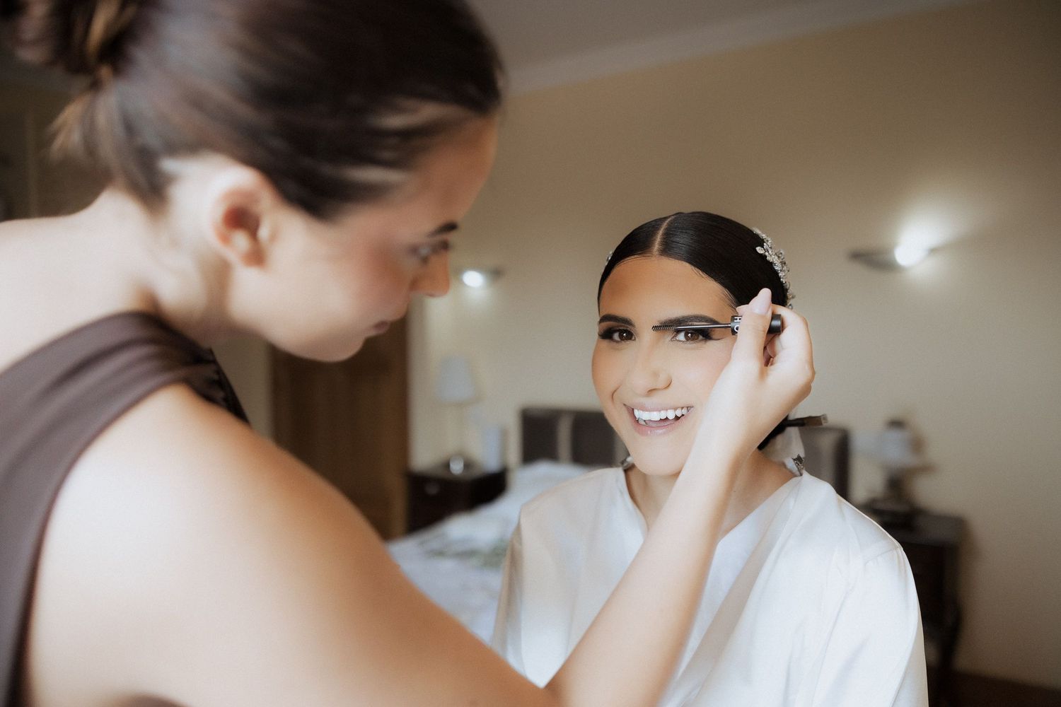 Professional makeup artist applying mascara to a bride during wedding day preparation.