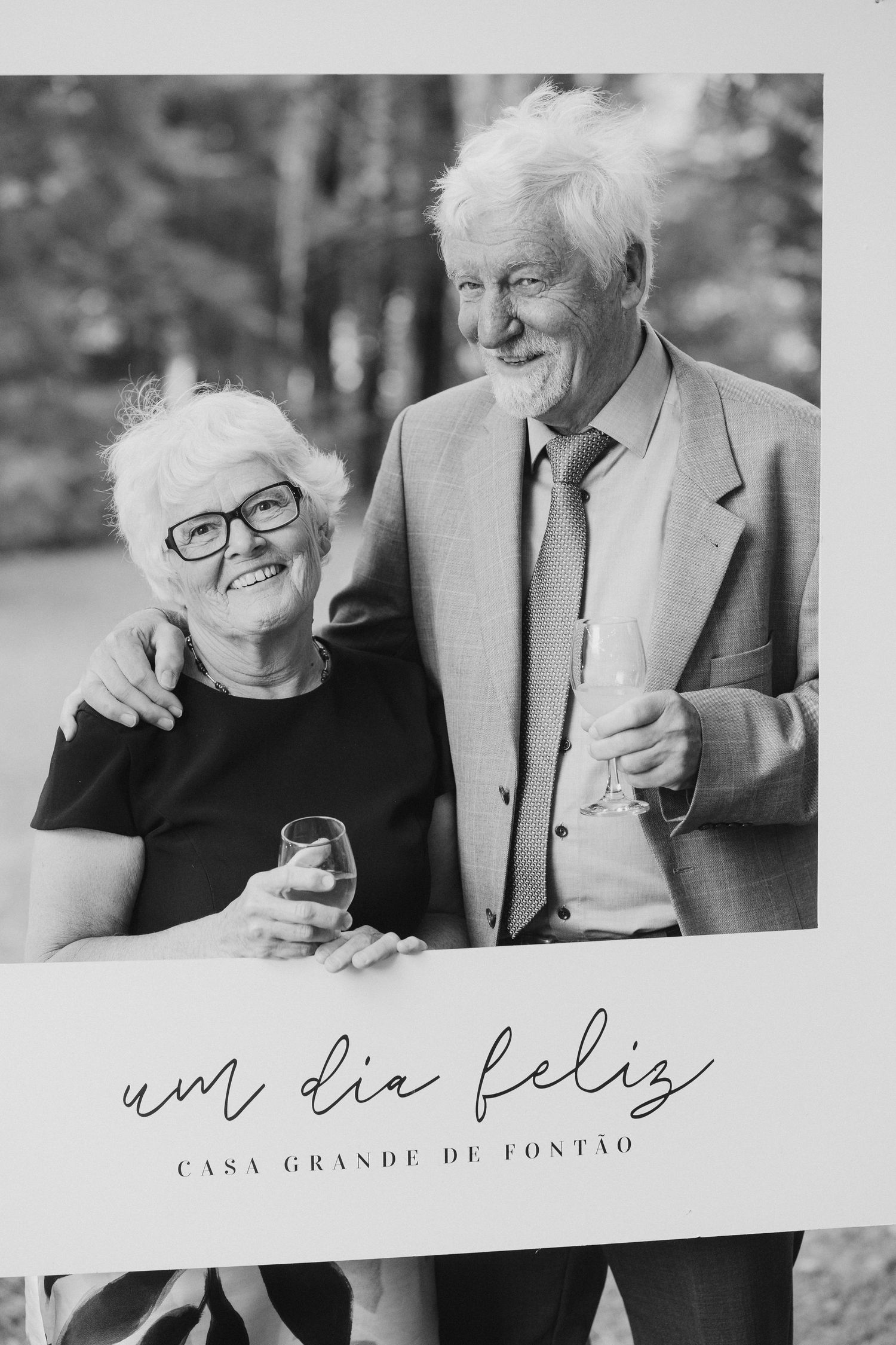 Fotografias em preto e branco mostram um casal de idosos rindo e se abraçando enquanto estão sentados juntos ao ar livre.