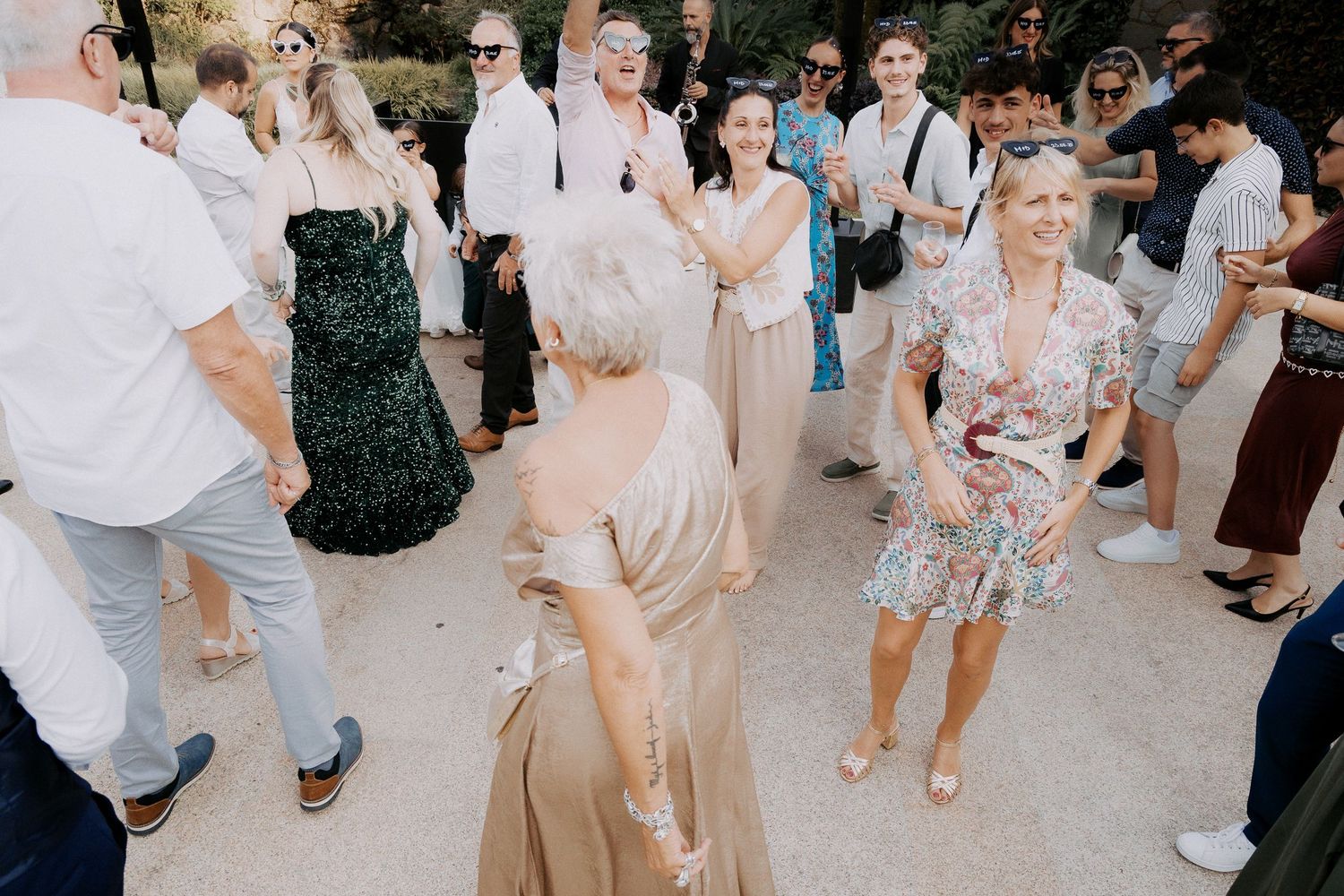 Wedding guests dance and celebrate on an outdoor patio during a summer reception party.
