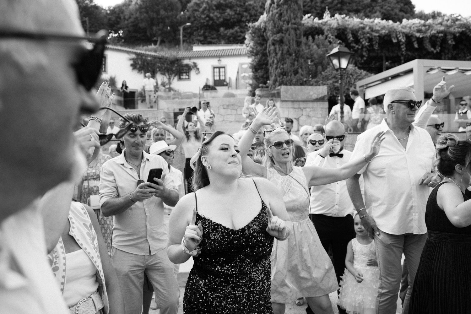 Wedding guests dance and celebrate together outdoors during a joyful summer reception celebration.