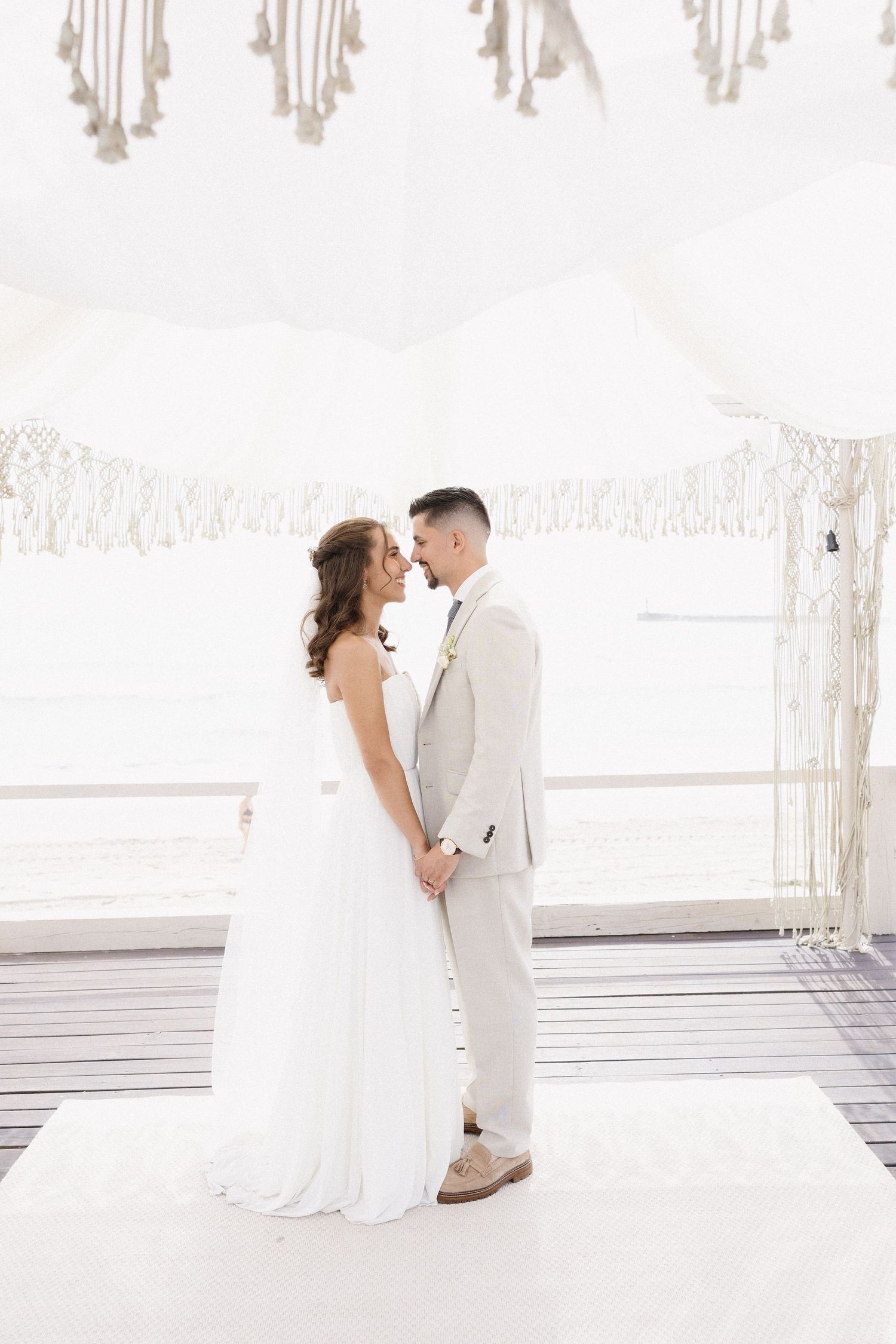 Casal elegante compartilhando momento íntimo sob um painel de macramê em casamento no Set Lounge Azurara em Vila do Conde