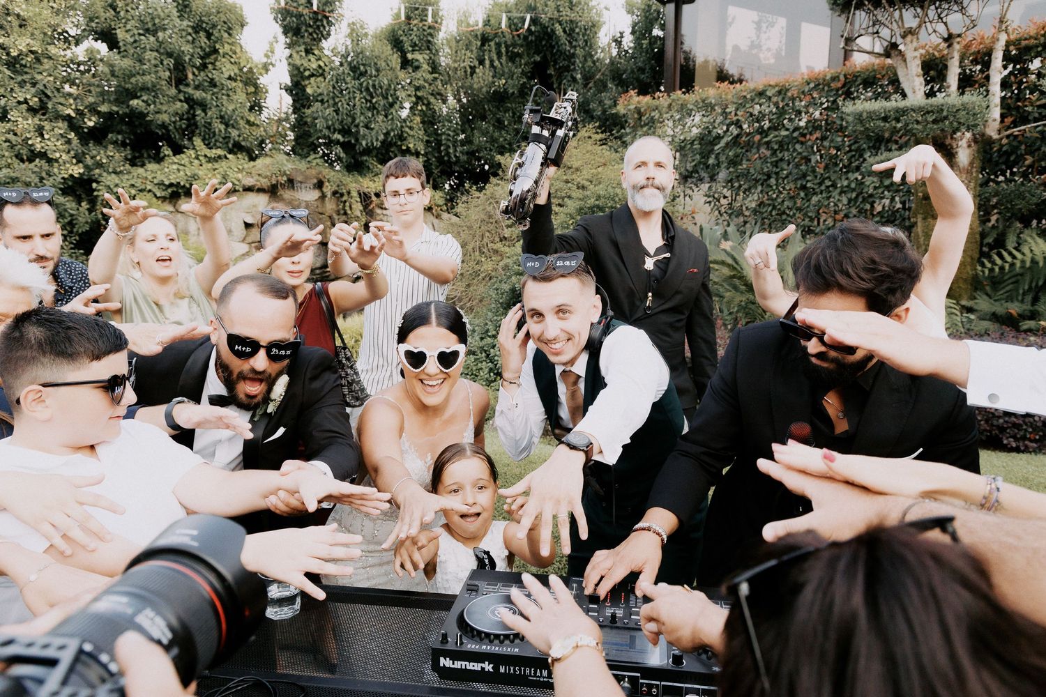 A group of wedding guests dancing and celebrating together at an outdoor reception.