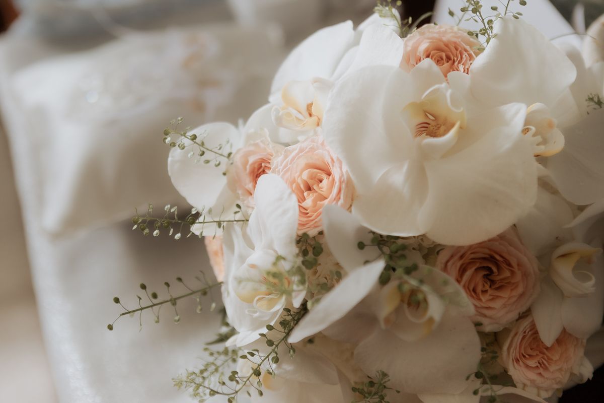 Elegante buquê de noiva com rosas cor-de-rosa e flores brancas, arranjado com delicadas flores de gipsofila sobre um fundo claro. All Got.