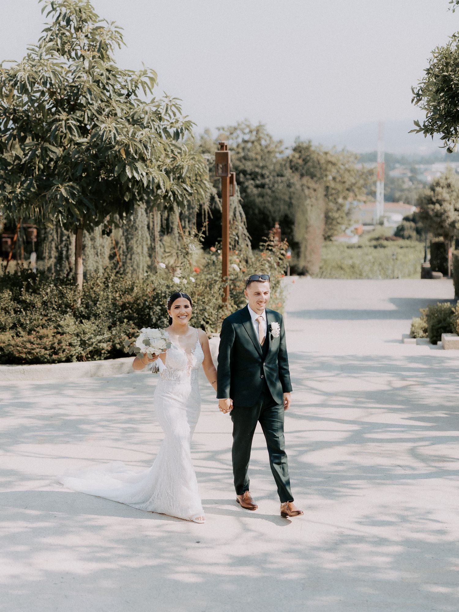 A couple shares a romantic first look moment in an outdoor garden setting with natural lighting and greenery.