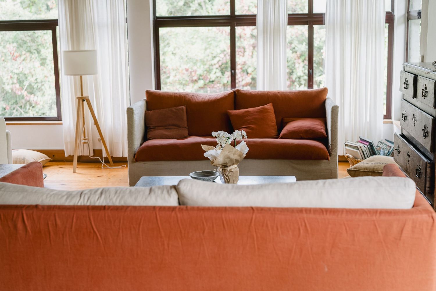 Cozy living room interior with brown leather sofa, large windows, and natural light flooding the space.