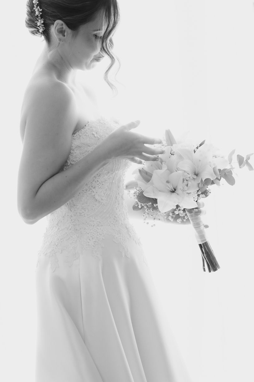 Foto preto e branco da noiva com um vestido de casamento sem alças segurando um delicado buquê. Casamento na Quinta do Cruzeiro.