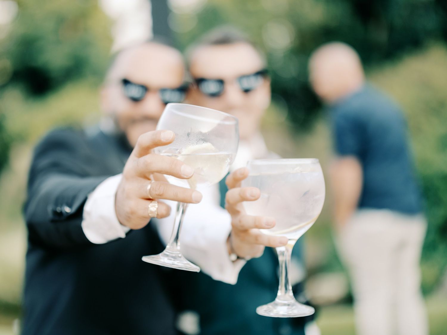People raise champagne glasses in a celebratory toast during an outdoor event.