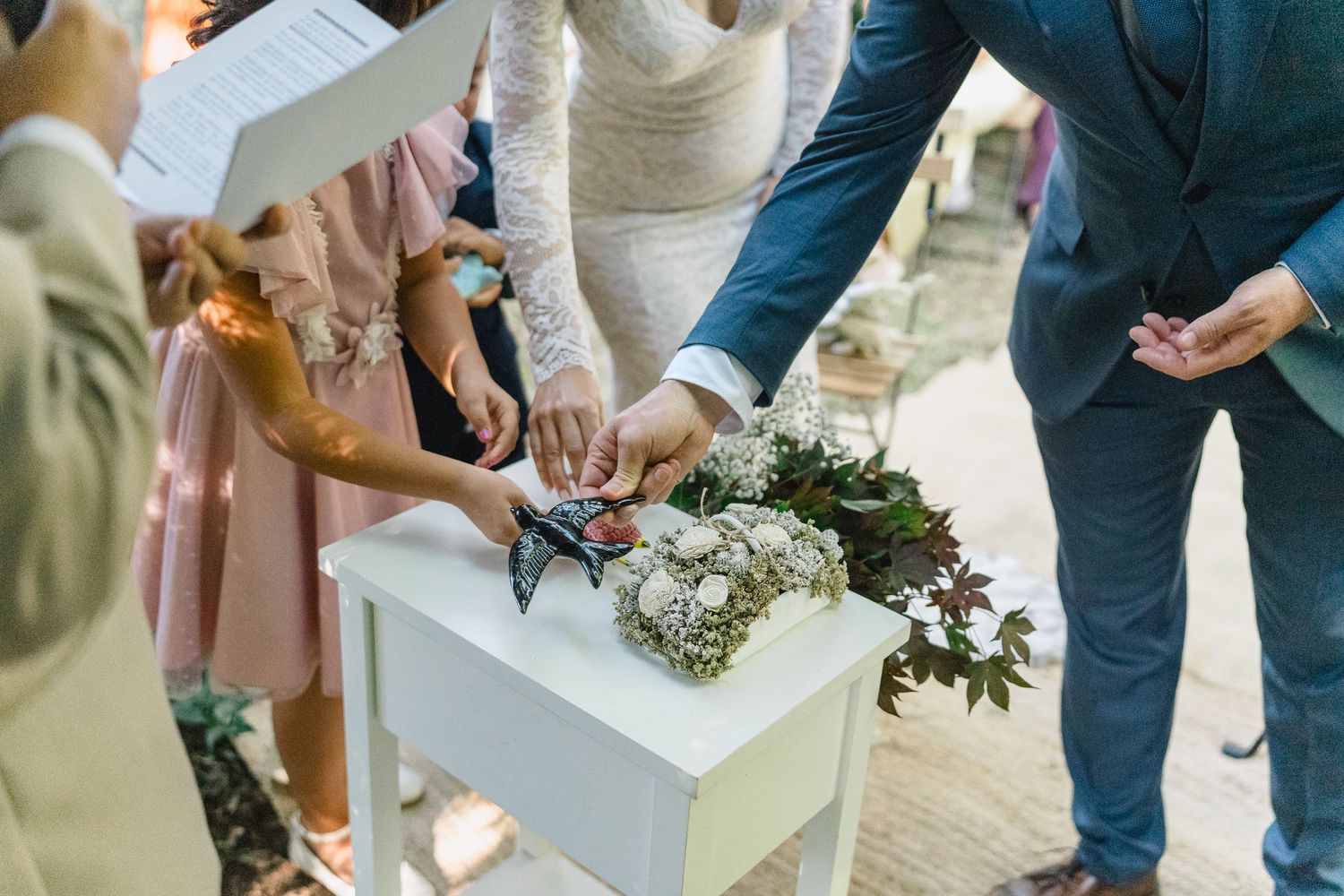 Wedding guests gather around a white cake table during an elegant reception celebration.