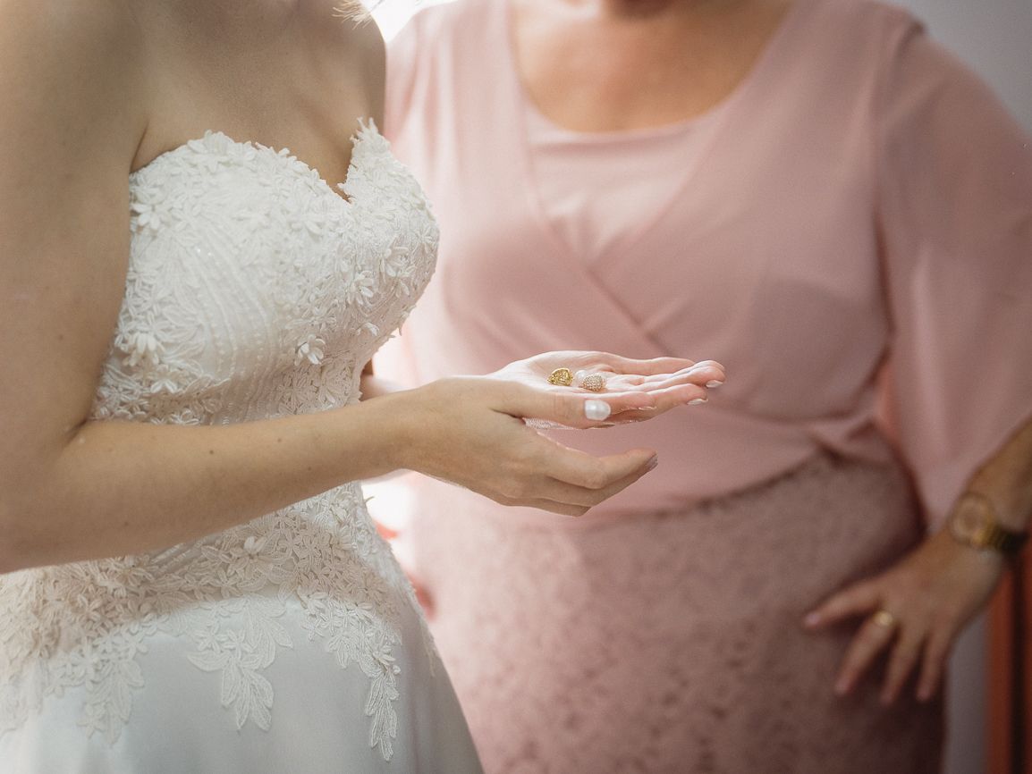 Detalhes de vestido de noiva exibe delicados padrões de renda e bordados em tecido branco com detalhes em rosa. Quinta do Cruzeiro