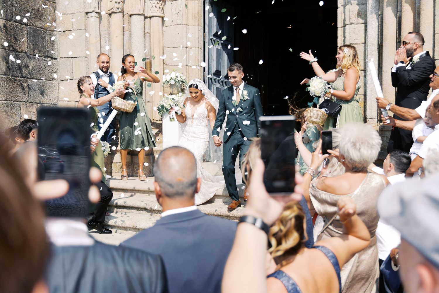 Wedding guests celebrate and dance together at an outdoor reception venue under string lights and stone walls.