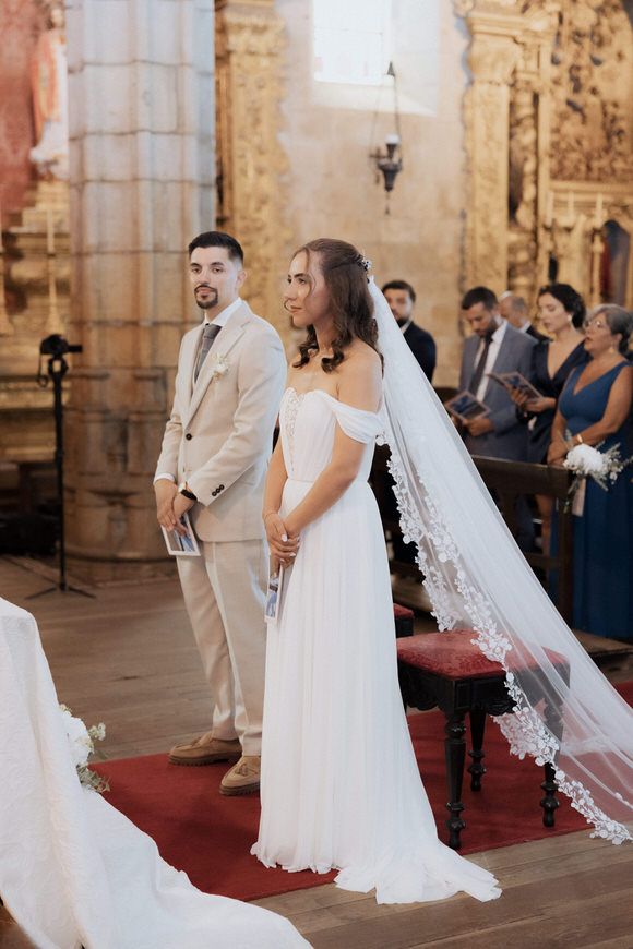 A cerimônia de casamento numaigreja de pedra ornamentada, corredor de tapete vermelho e decoração elegante. Casamento em Barcelos.
