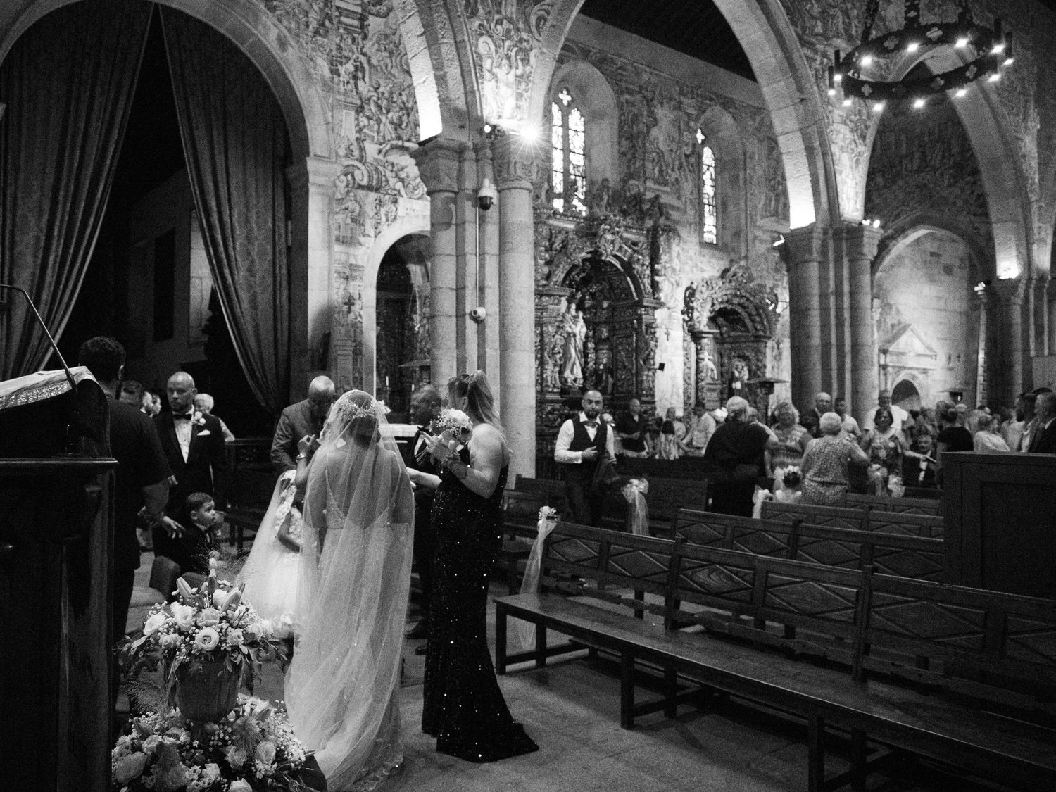 A series of black and white wedding ceremony photos showing moments inside a grand stone church with elegant decor.