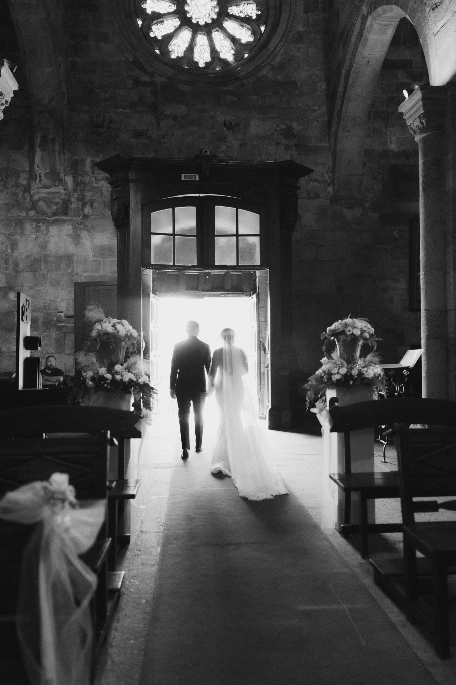Foto a preto e branco do interior de uma igreja, mostrando silhuetas dos noivos a caminhar sob a luz dramática da igreja de Esposende