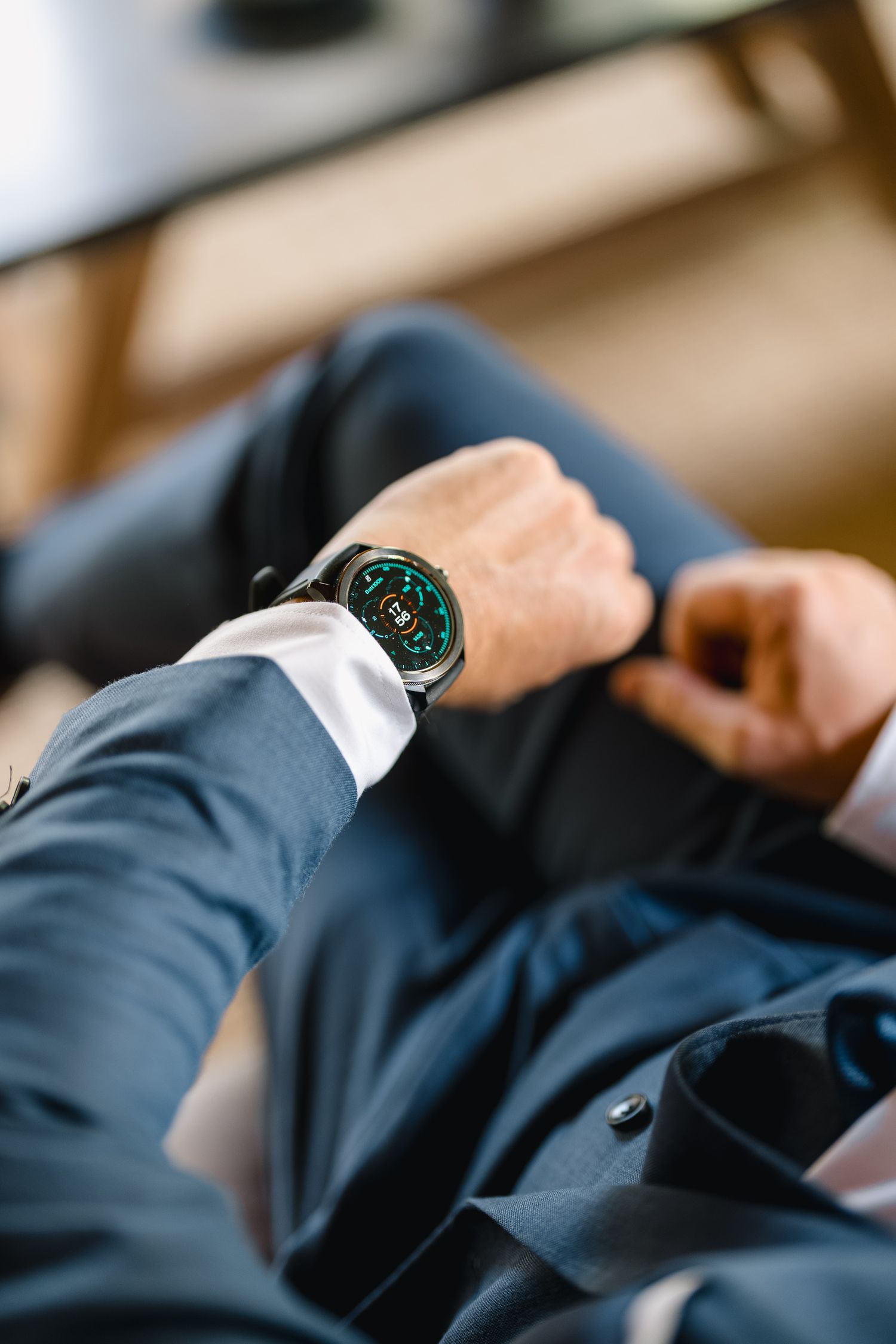 Close-up view of a person's wrist wearing a luxury watch with a navy blue suit sleeve.