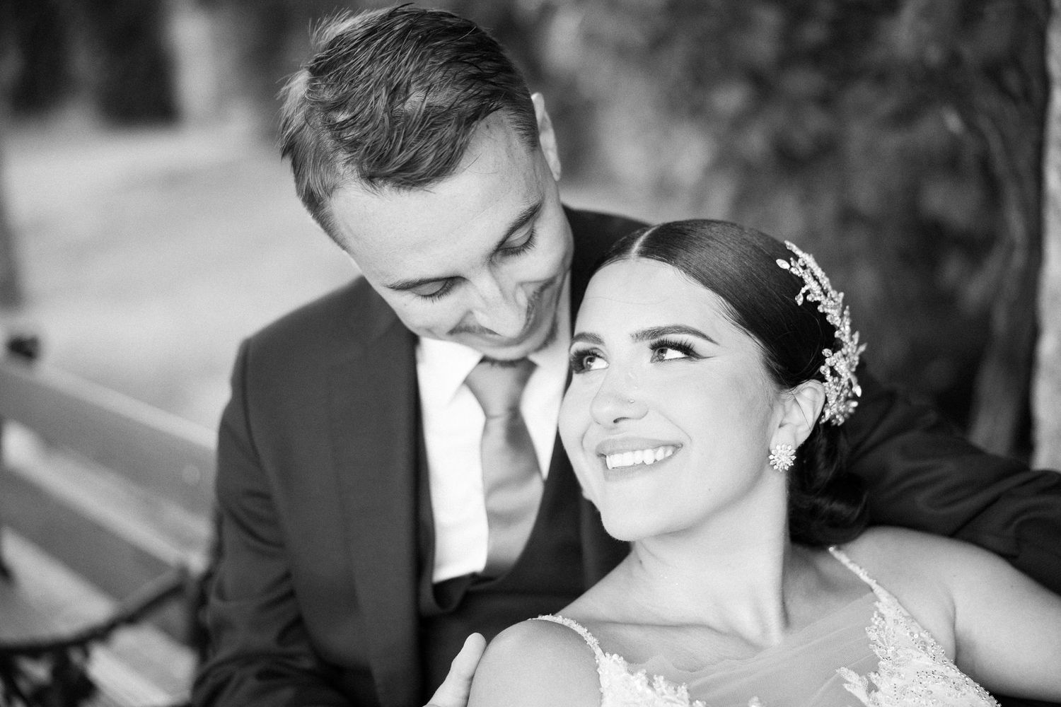 A romantic black and white wedding portrait of a couple sharing a joyful moment together outdoors.