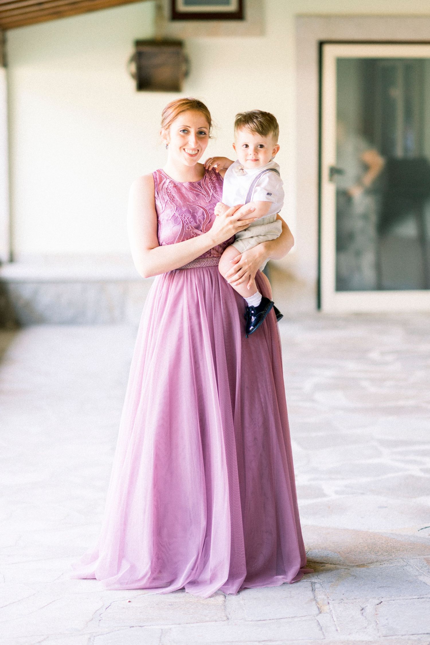 Two people in flowing pink and purple dresses share tender moments in an elegant indoor setting.