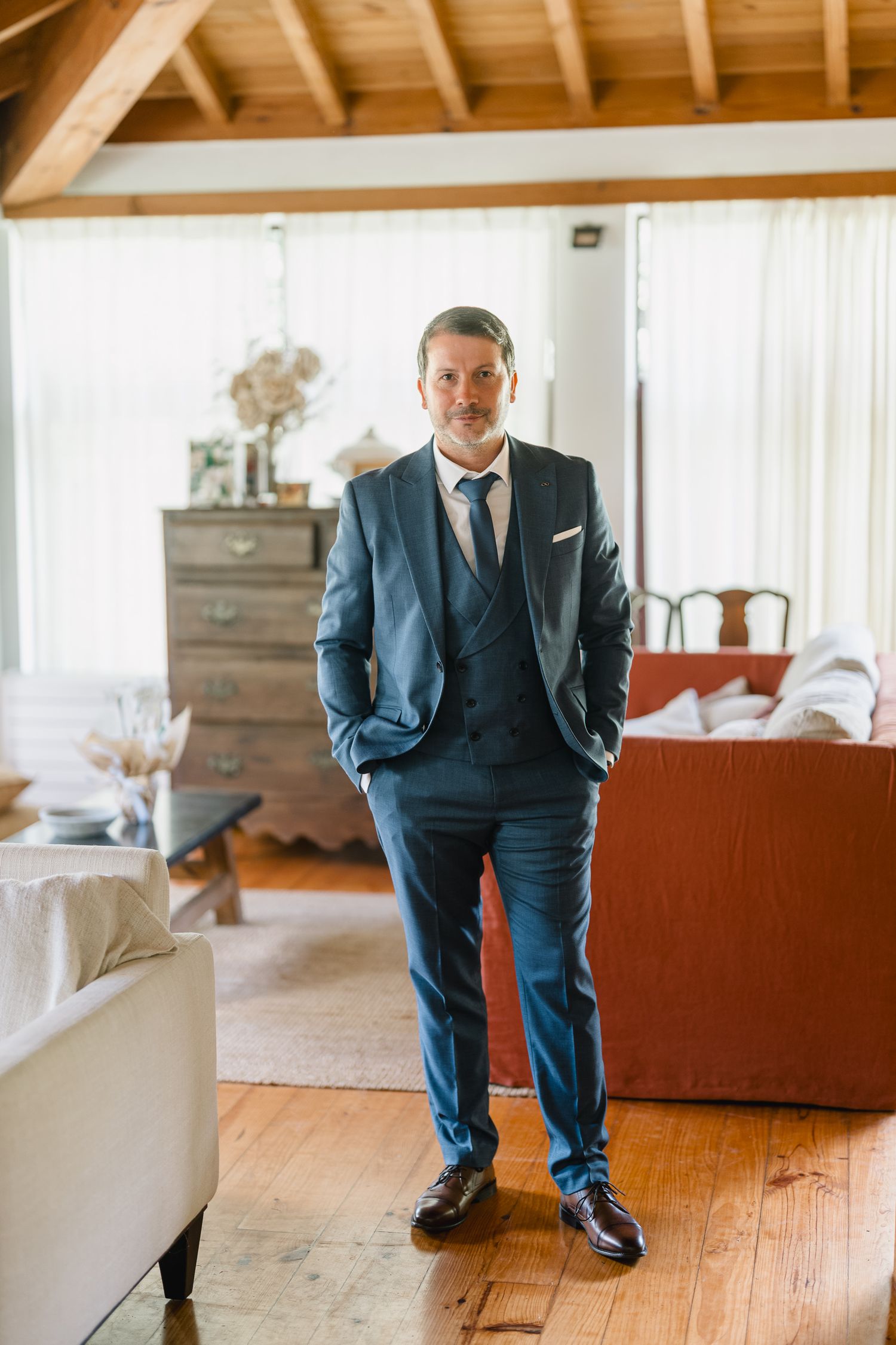 Professional groom getting ready on wedding day showing polished dress shoes and navy suit pants on hardwood floor.