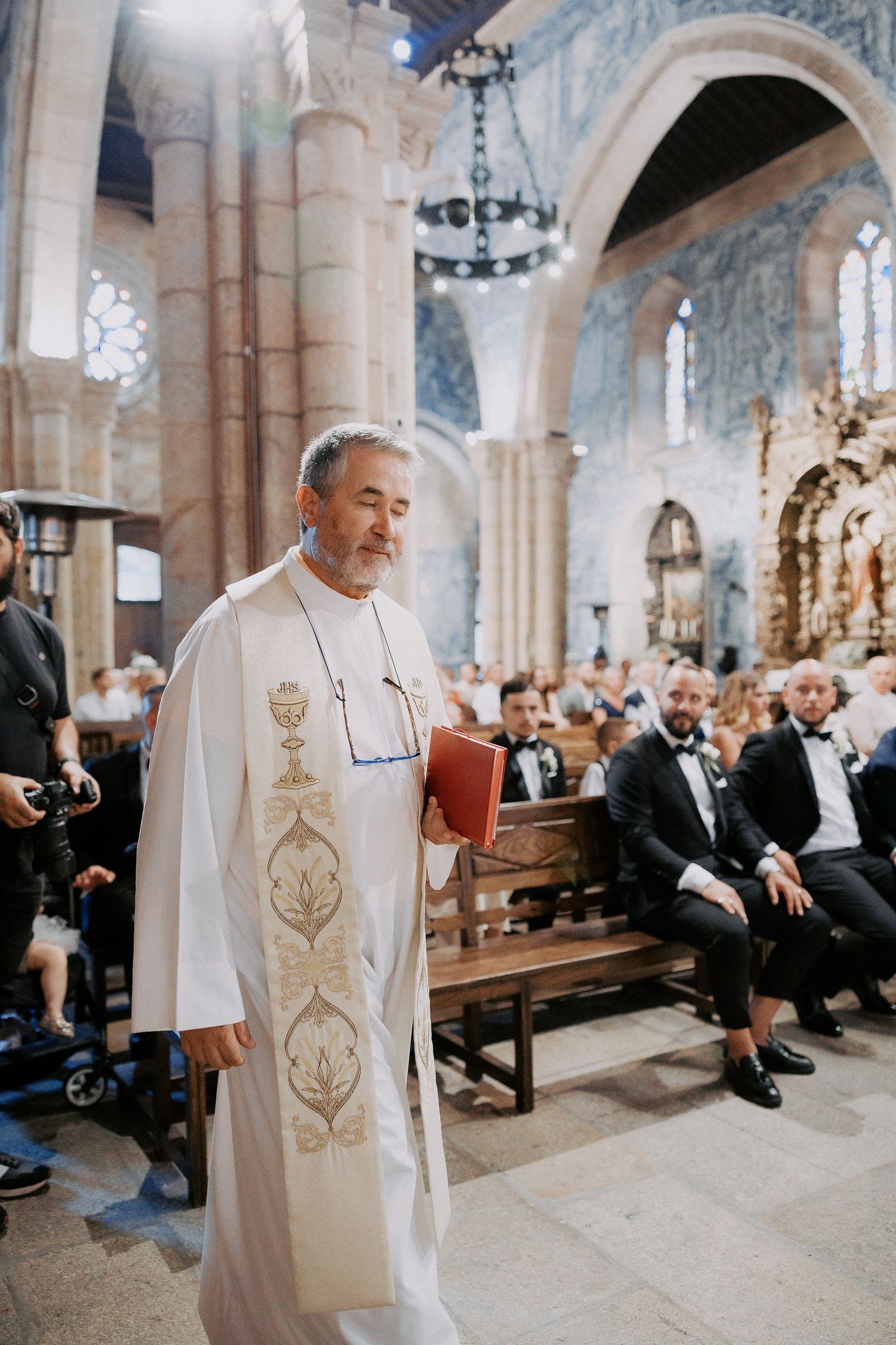 A sequence of photos showing a person in white ceremonial robes walking through a grand church interior during a service.