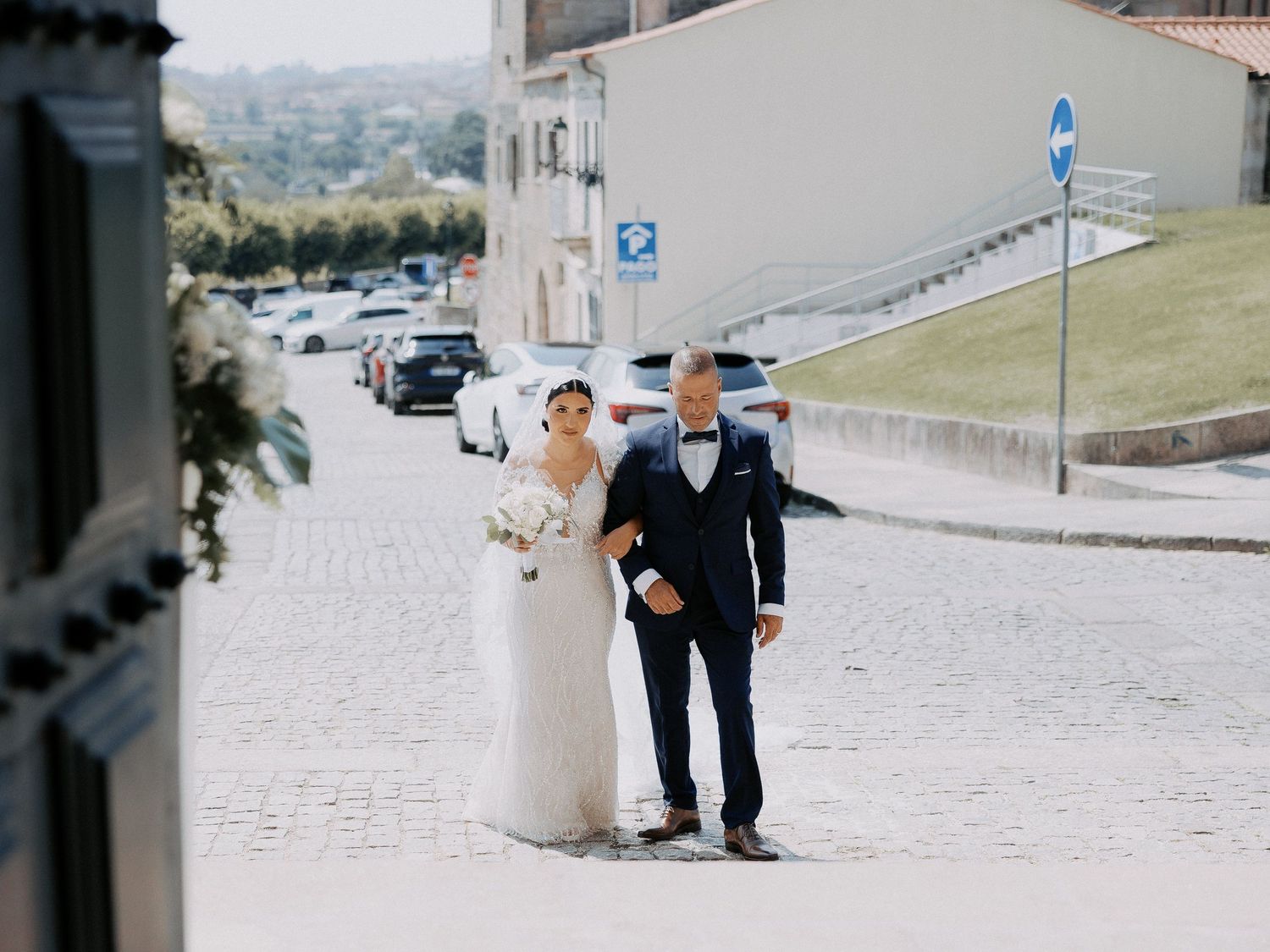A couple in wedding attire walks together on a cobblestone path on their special day.