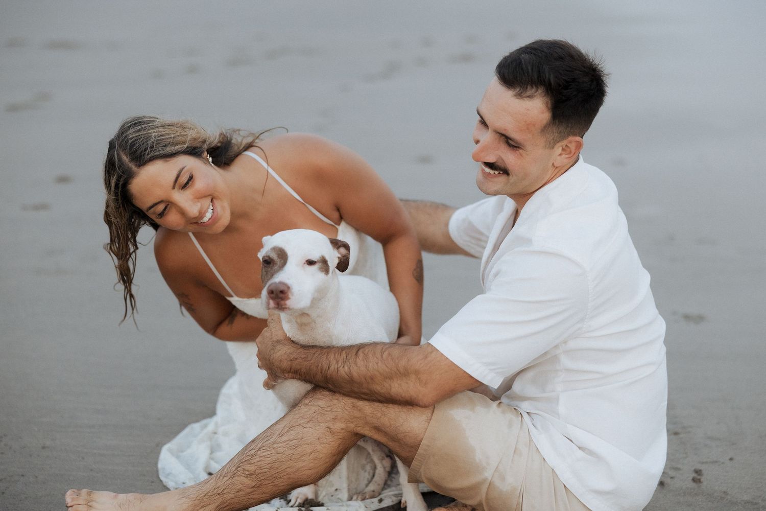 Casal compartilha momentos íntimos enquanto brinca nas ondas do mar durante uma sessão de fotos na praia.