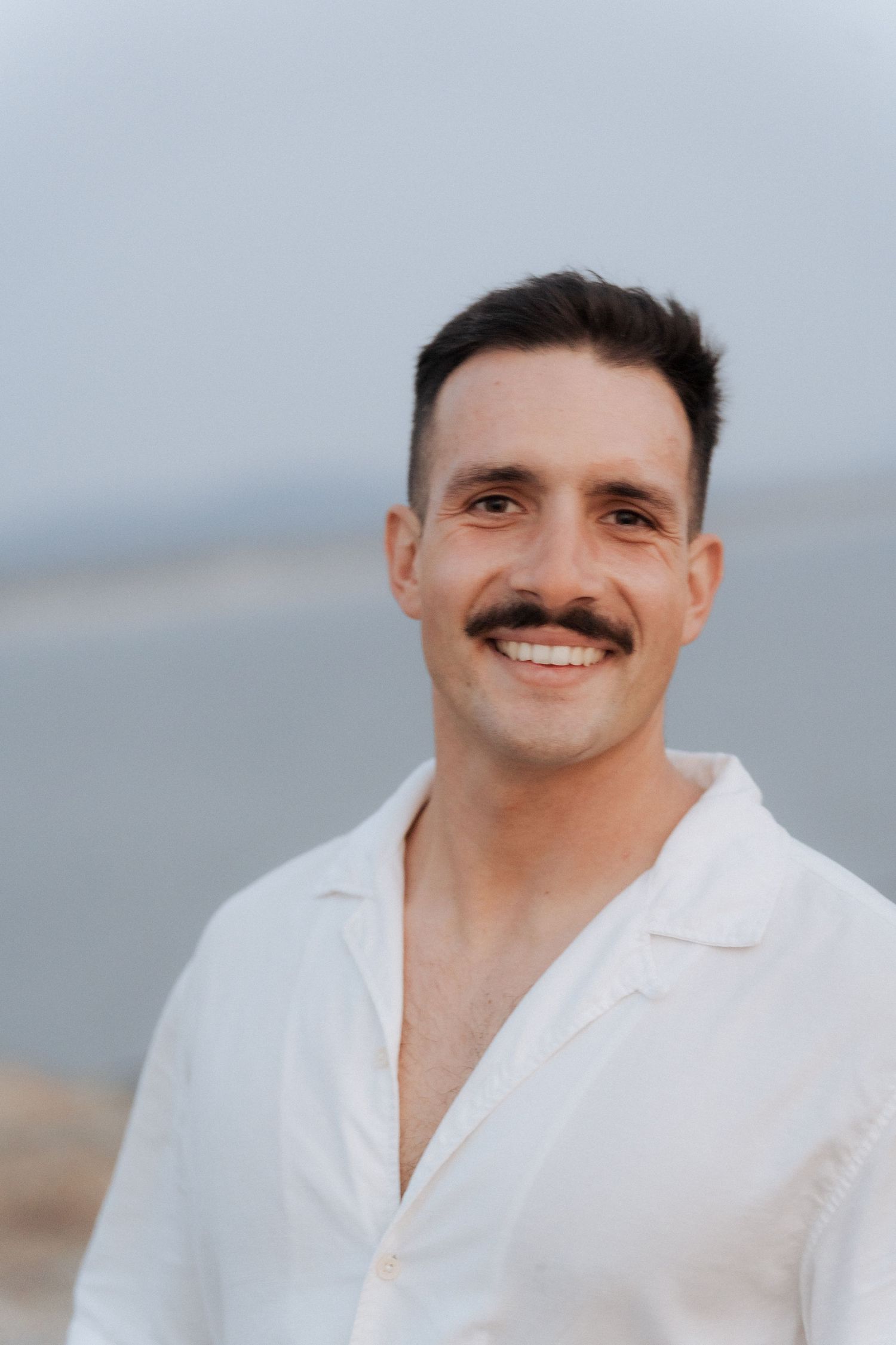 Série de retratos mostrando expressões faciais em camisa branca contra fundo neutro. Sessão fotográfica na praia