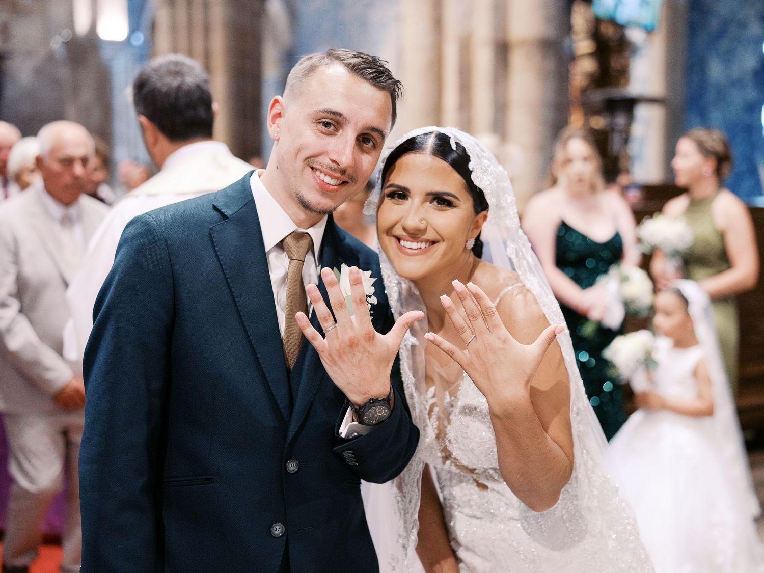 A happy couple celebrates during their wedding reception showing off their rings to the camera.
