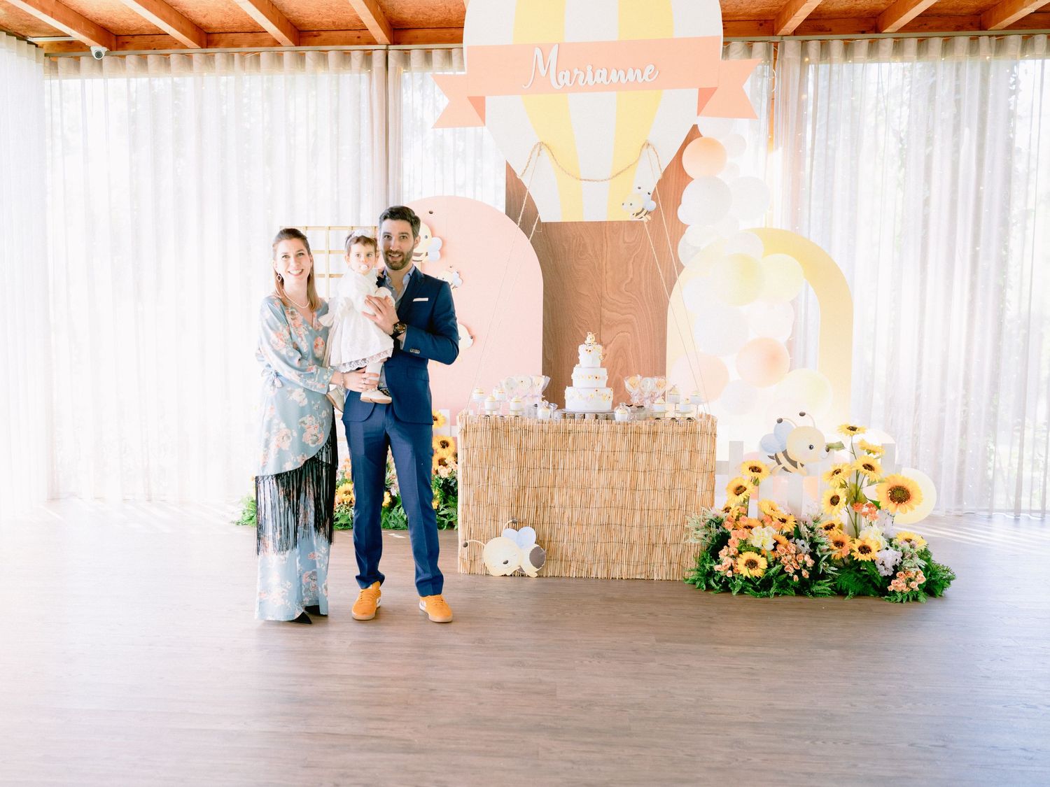 A wedding ceremony setup with wooden beams overhead, white drapes, and floral arrangements in a rustic indoor venue.