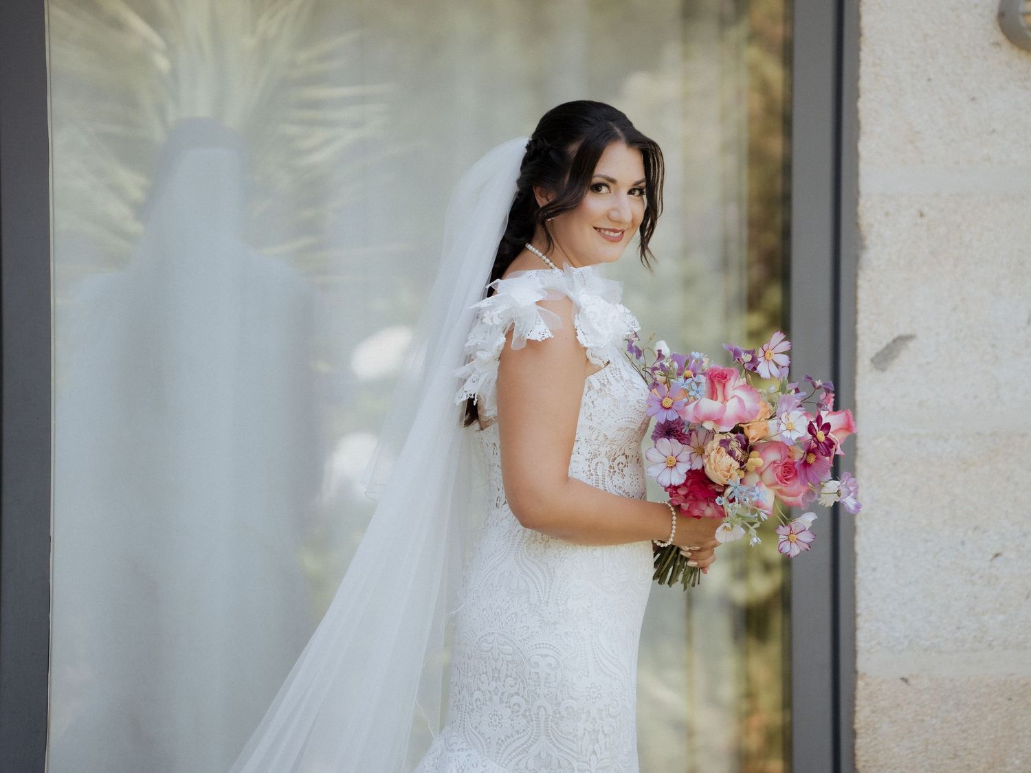 Uma noiva em um vestido de casamento branco segura um buquê rosa e roxo, na Quinta do Cruzeiro em Vila Praia de Ancora.