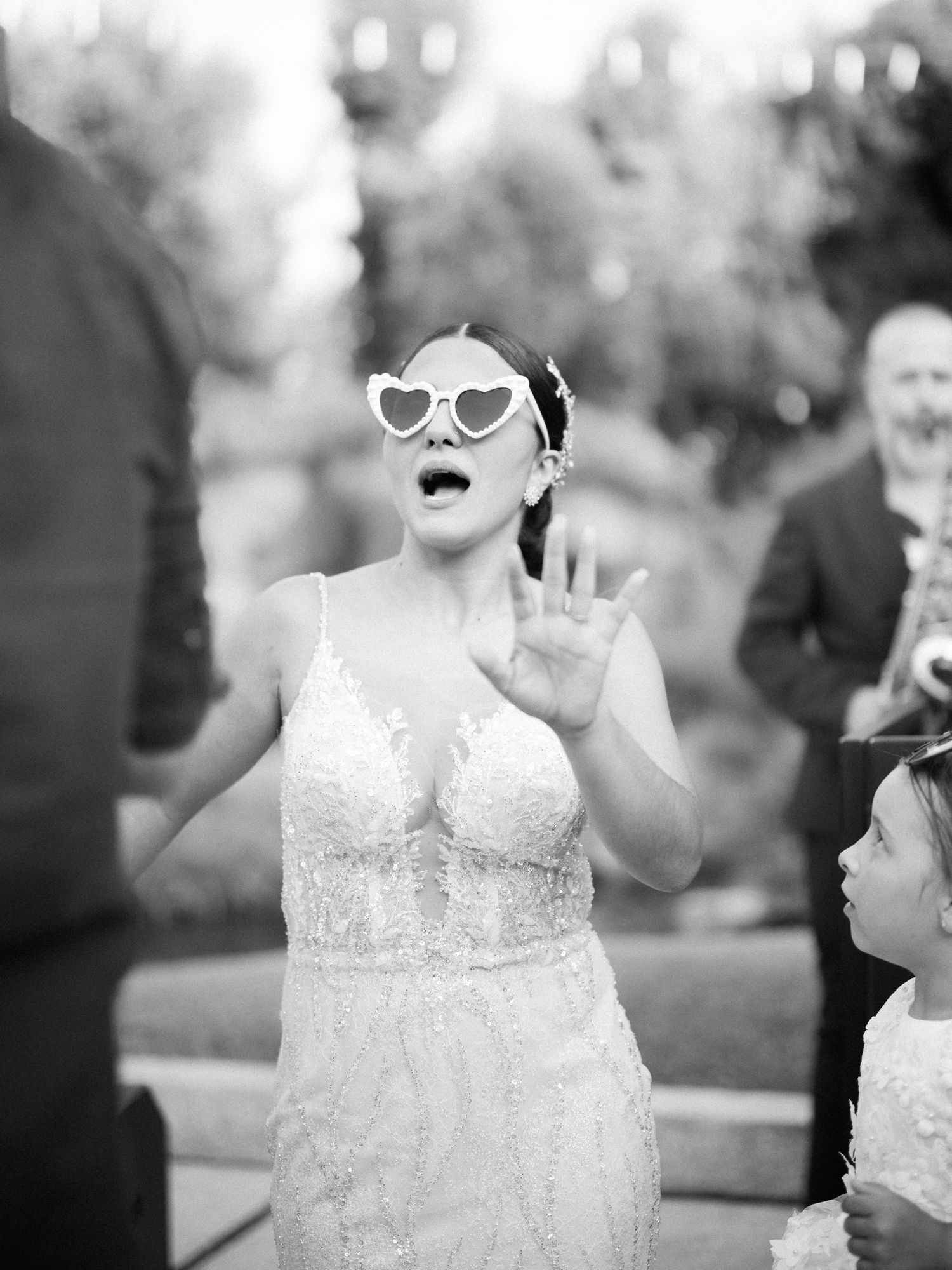 Black and white wedding photo series showing candid moments of a bride in a lace dress enjoying celebratory moments.
