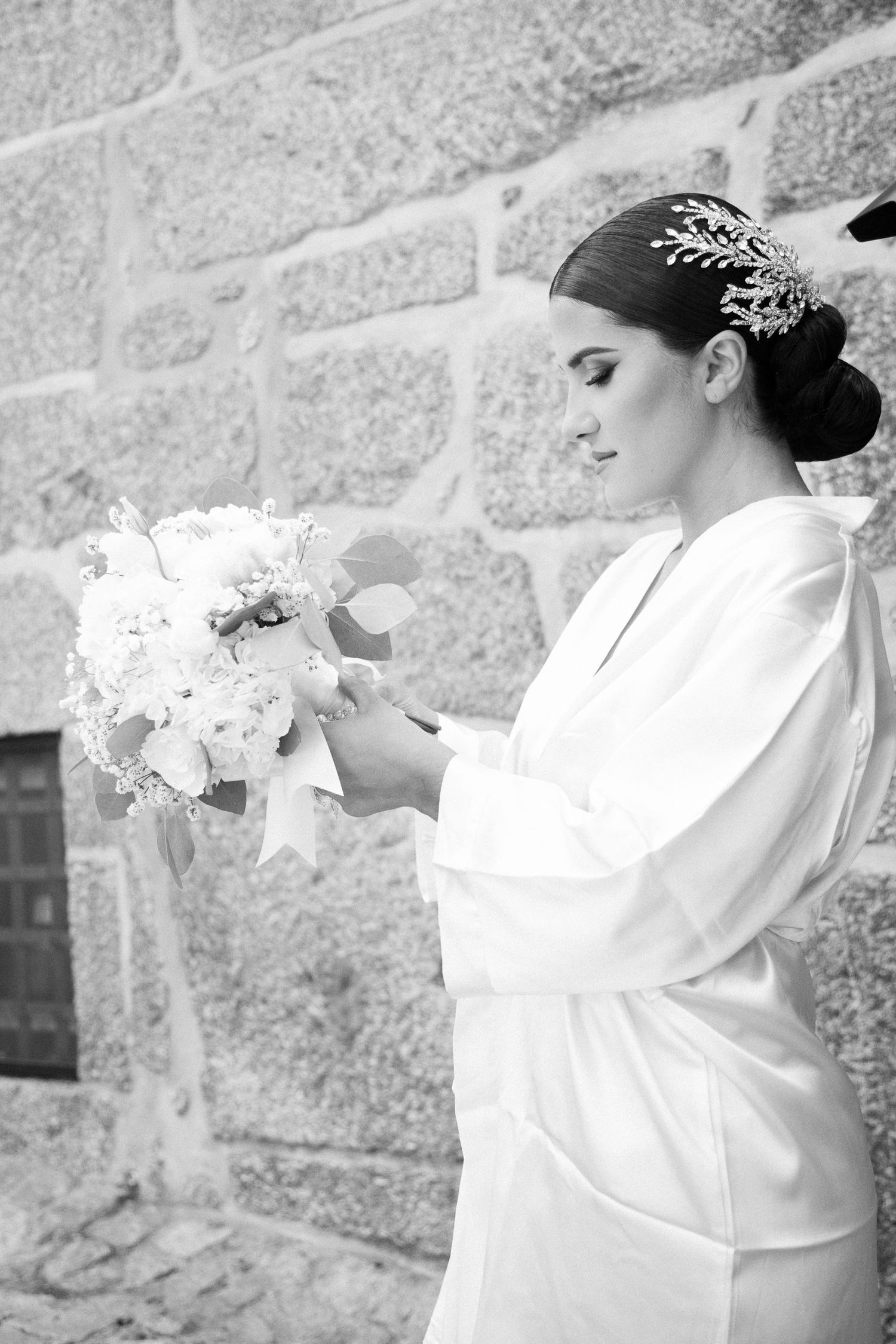 A series of black and white photos showing a bride in a white robe with flowers against a stone wall.
