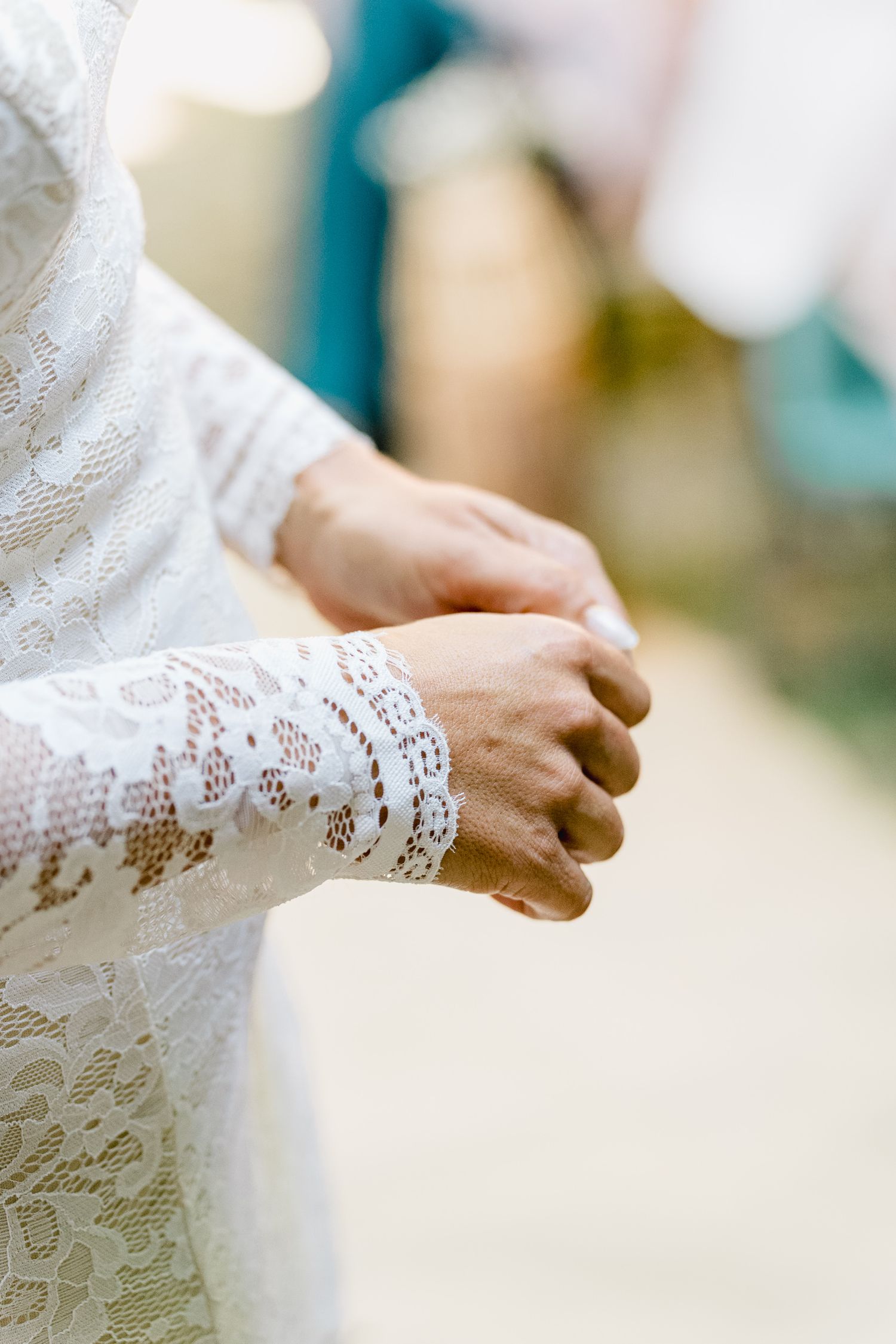 Close-up view of delicate lace sleeve details on a white wedding dress showing intricate floral patterns.