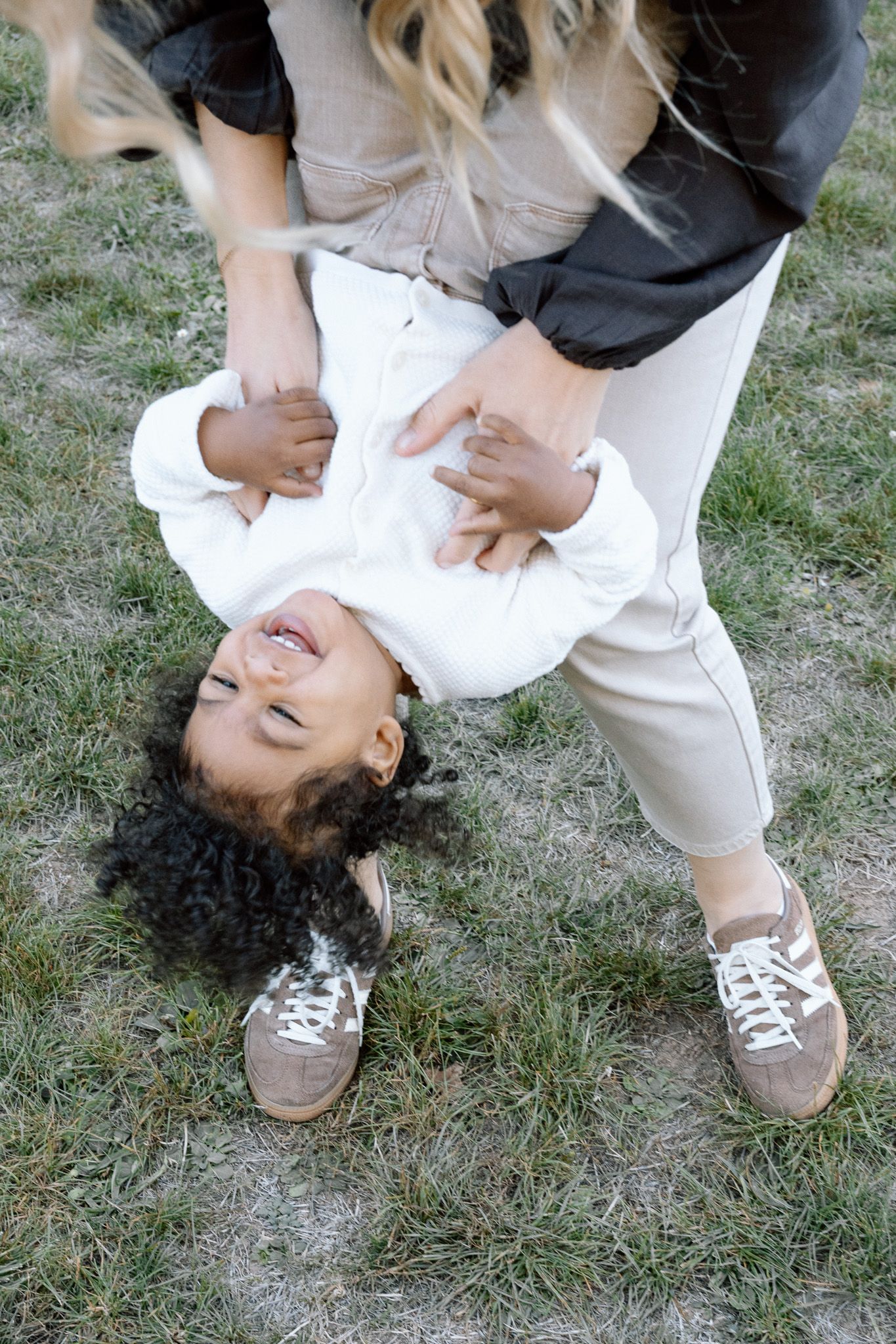 Laughing toddler hanging upside down in his mother’s arms, Familienfotografie