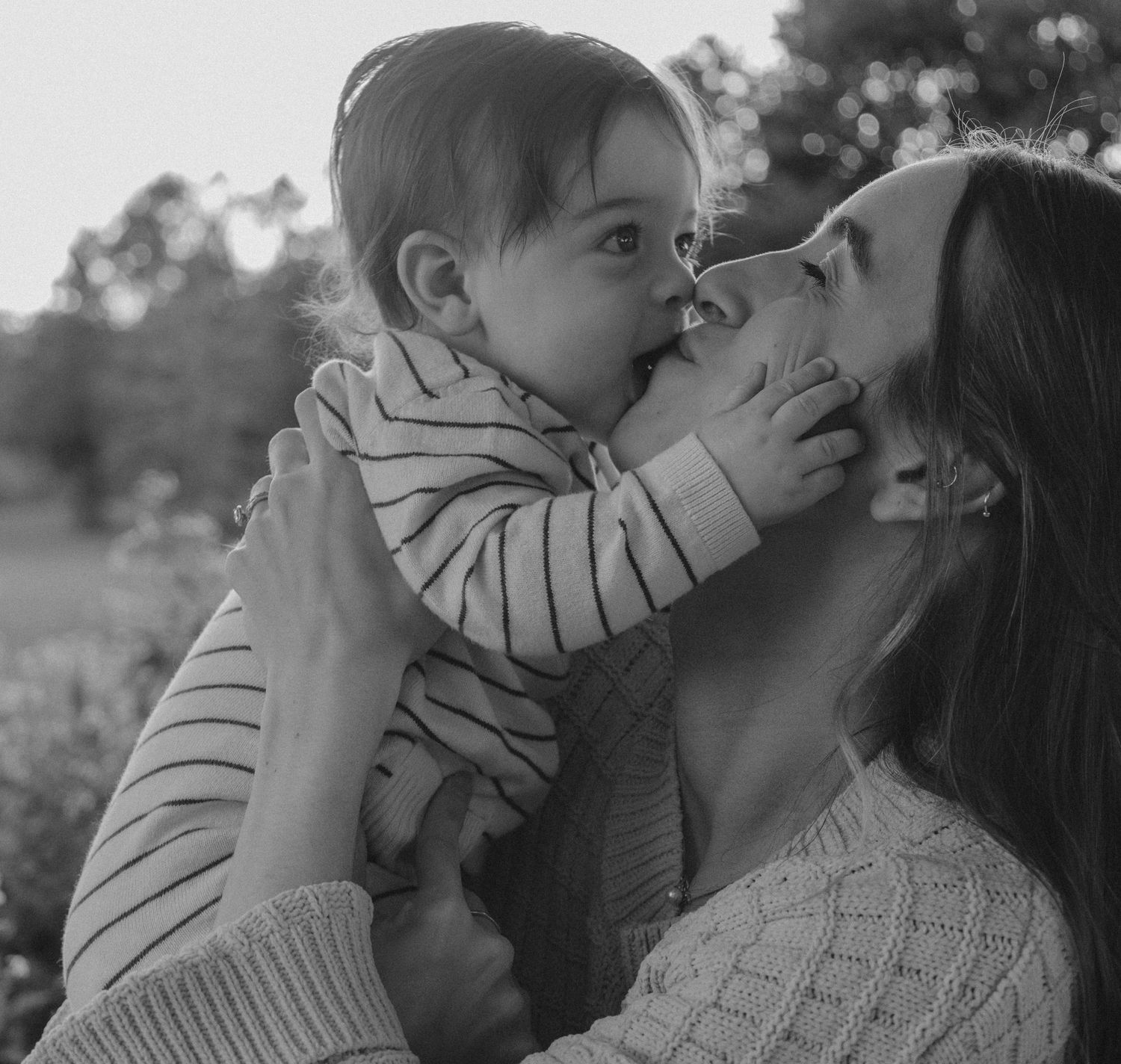 Black and white photo of mother and baby sharing a sweet nose-to-nose moment.