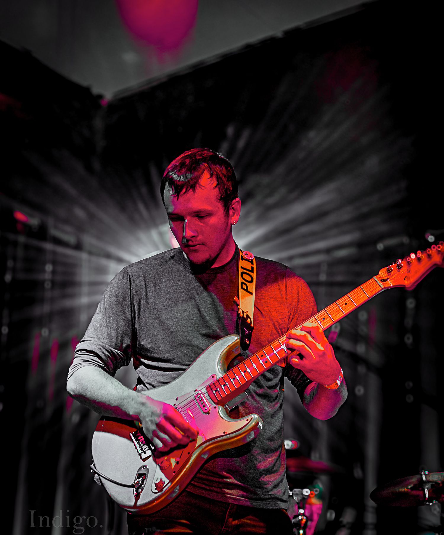 Guitarist playing electric guitar with dramatic red spotlight and starburst lighting effects.