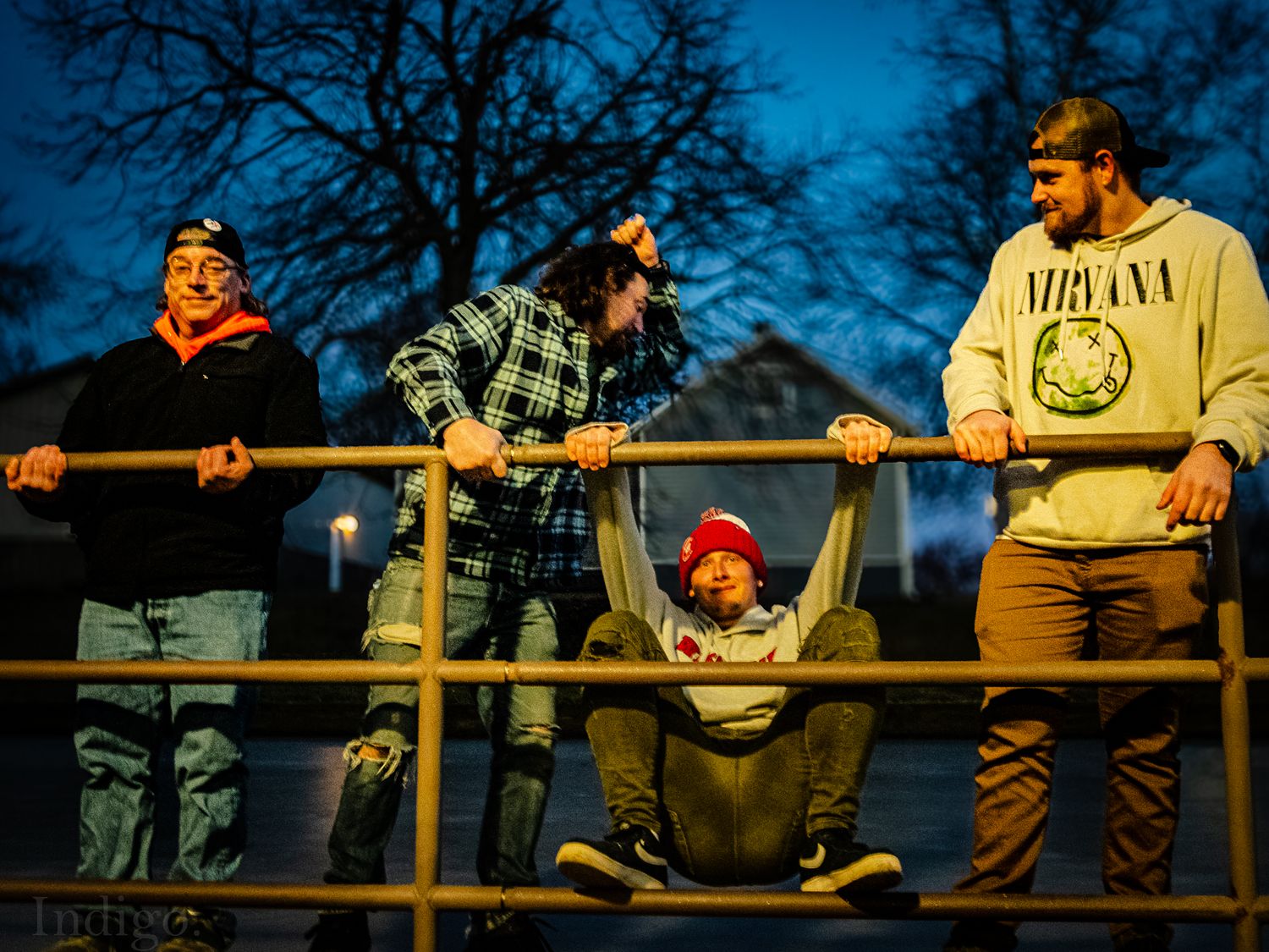 Group of friends hanging out on playground equipment at dusk.