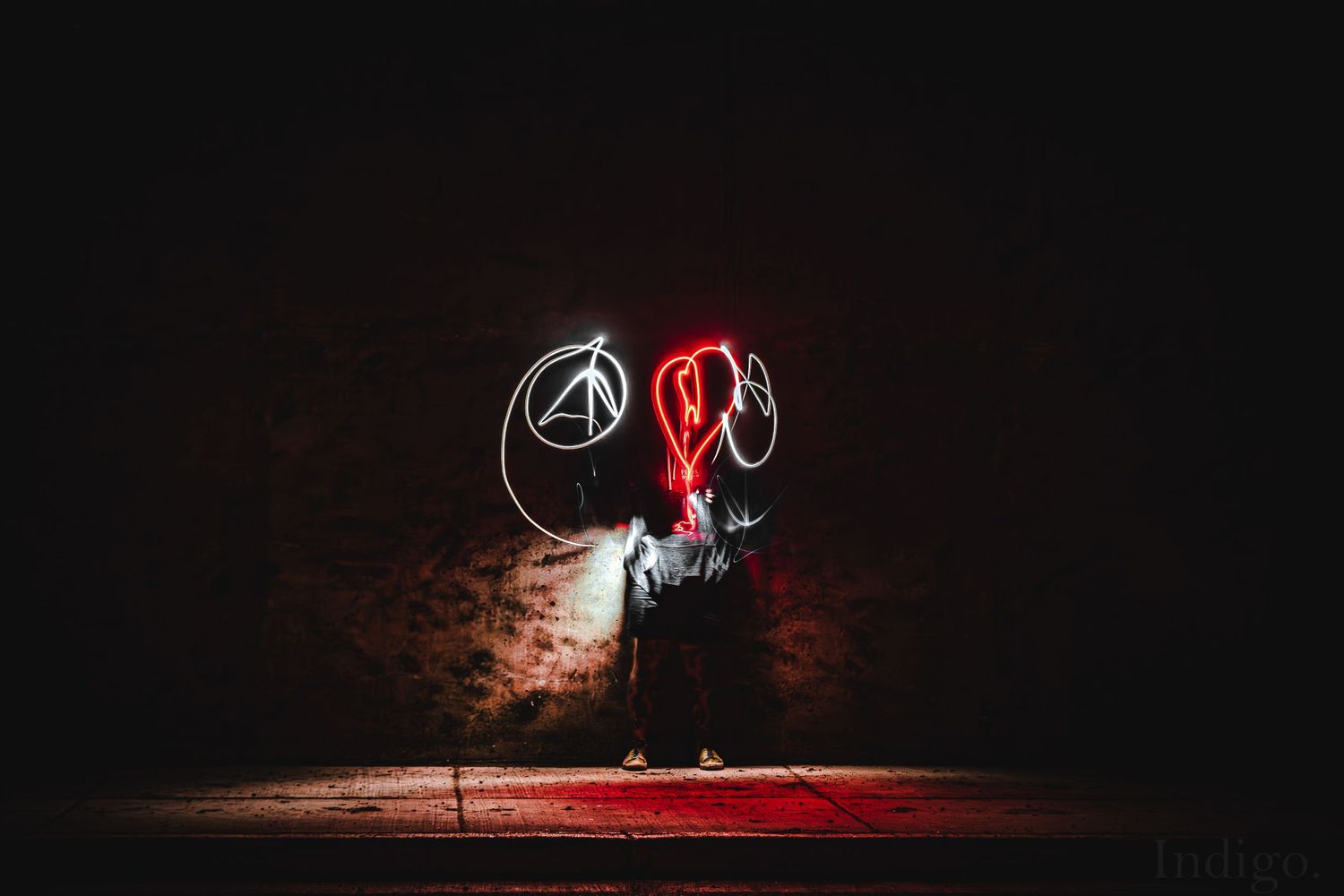 Red illuminated figures performing with light trails in a dark forest setting.