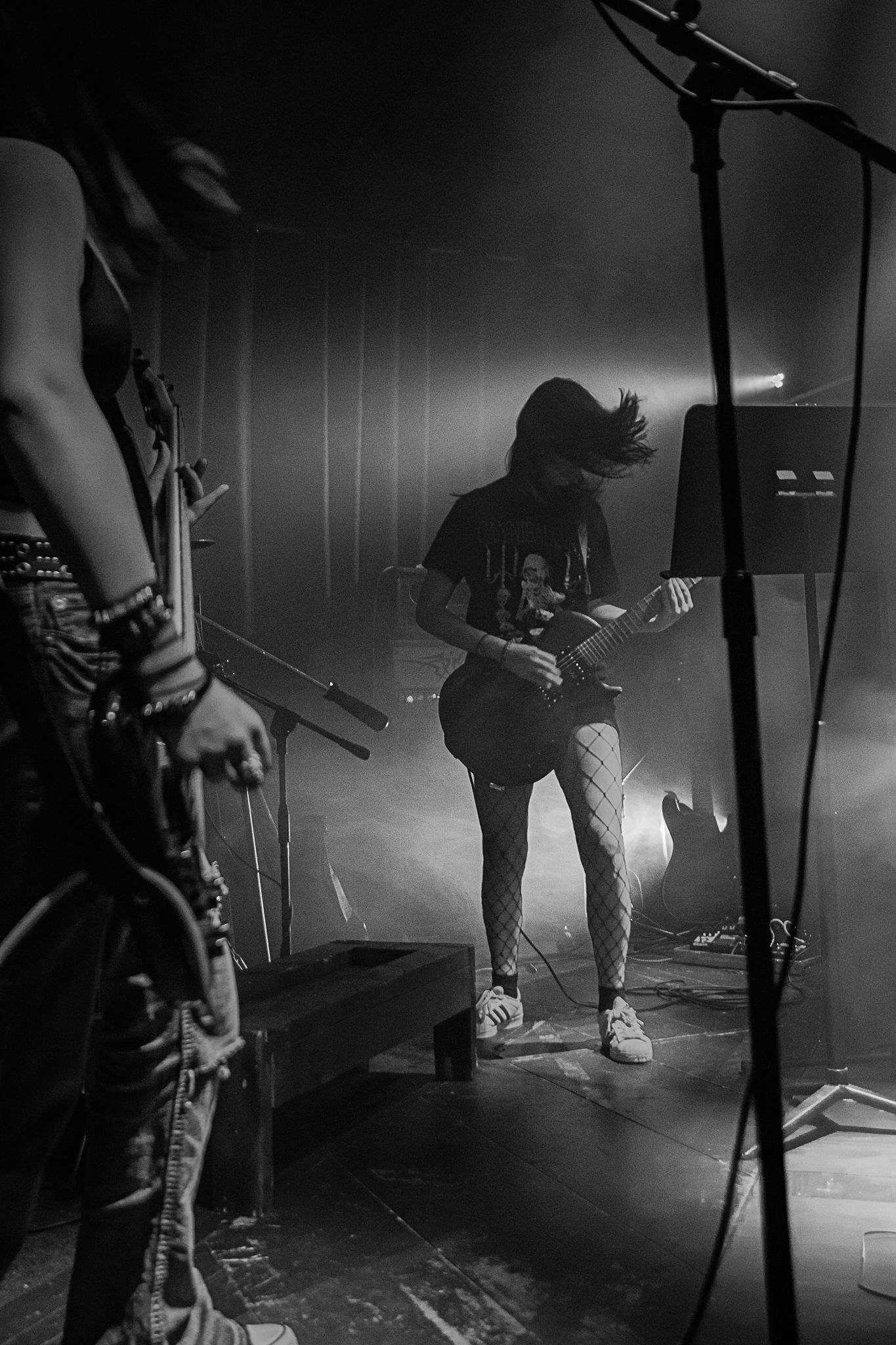 Rock band performing on stage with dramatic backlighting and fog effects.
