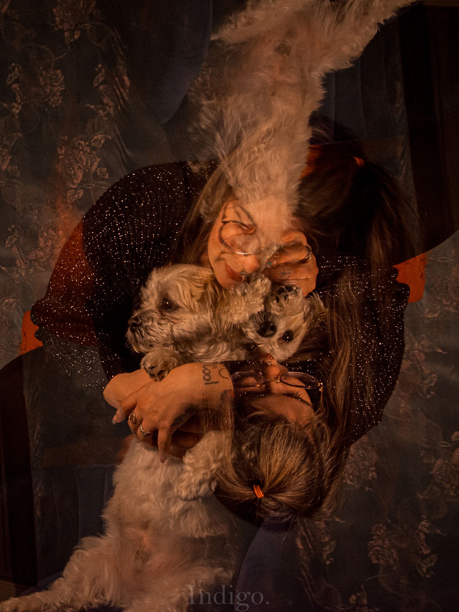Artistic portrait with smoke effects and a small dog being held in dark moody lighting with orange tones.