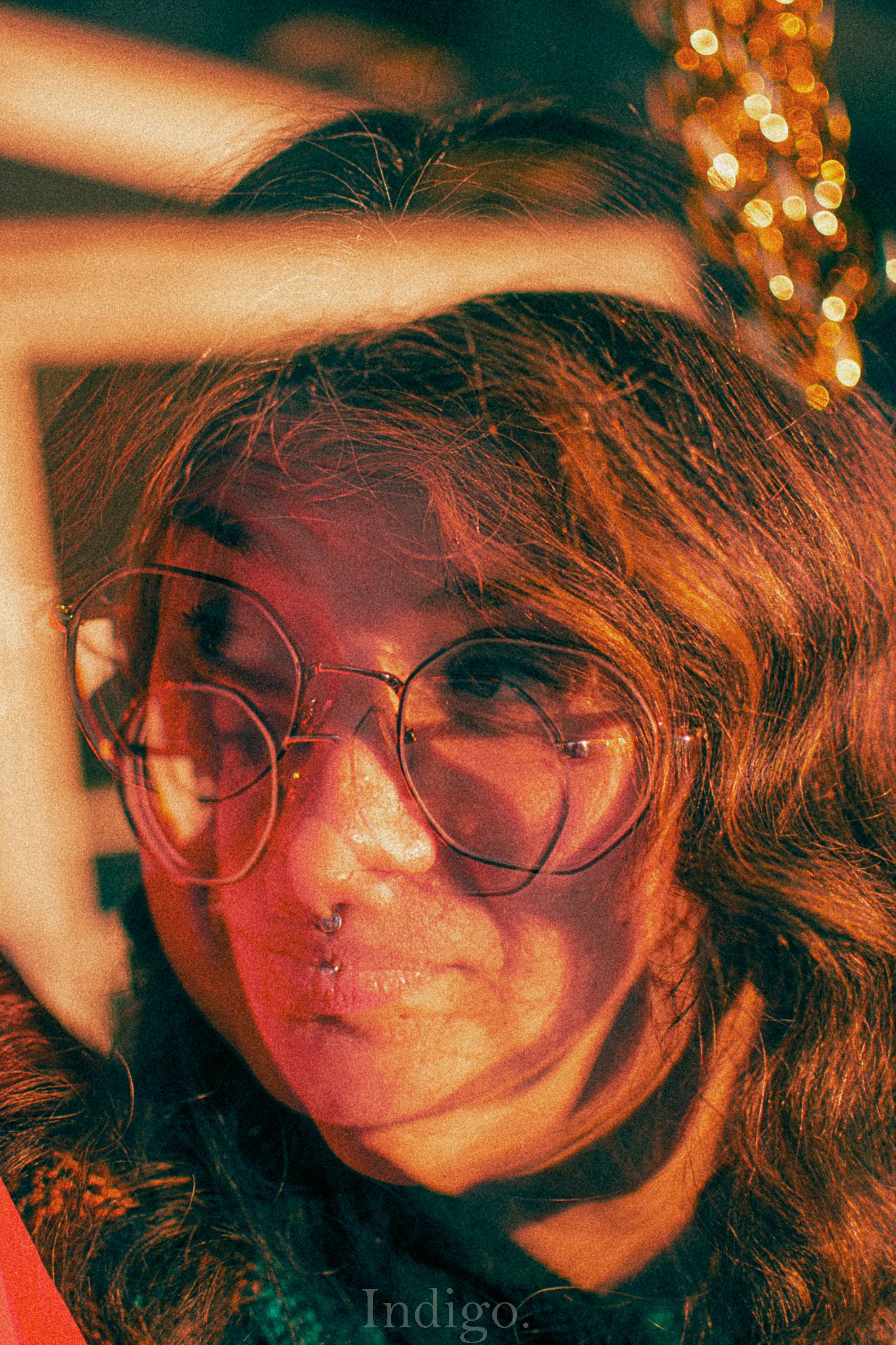 Artistic portrait in warm lighting with bokeh effects and glasses creating a dreamy atmosphere.