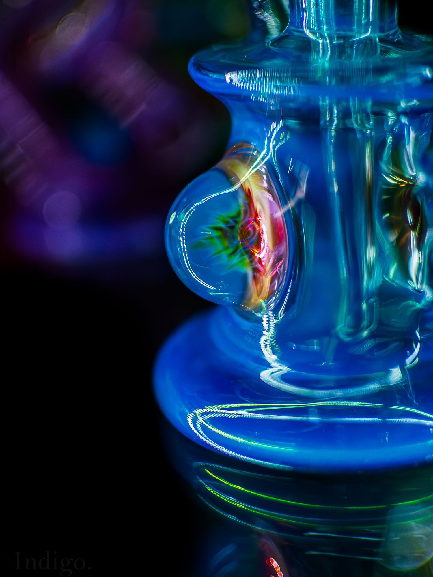 Abstract blue glass or crystal object with colorful light reflections against dark background.
