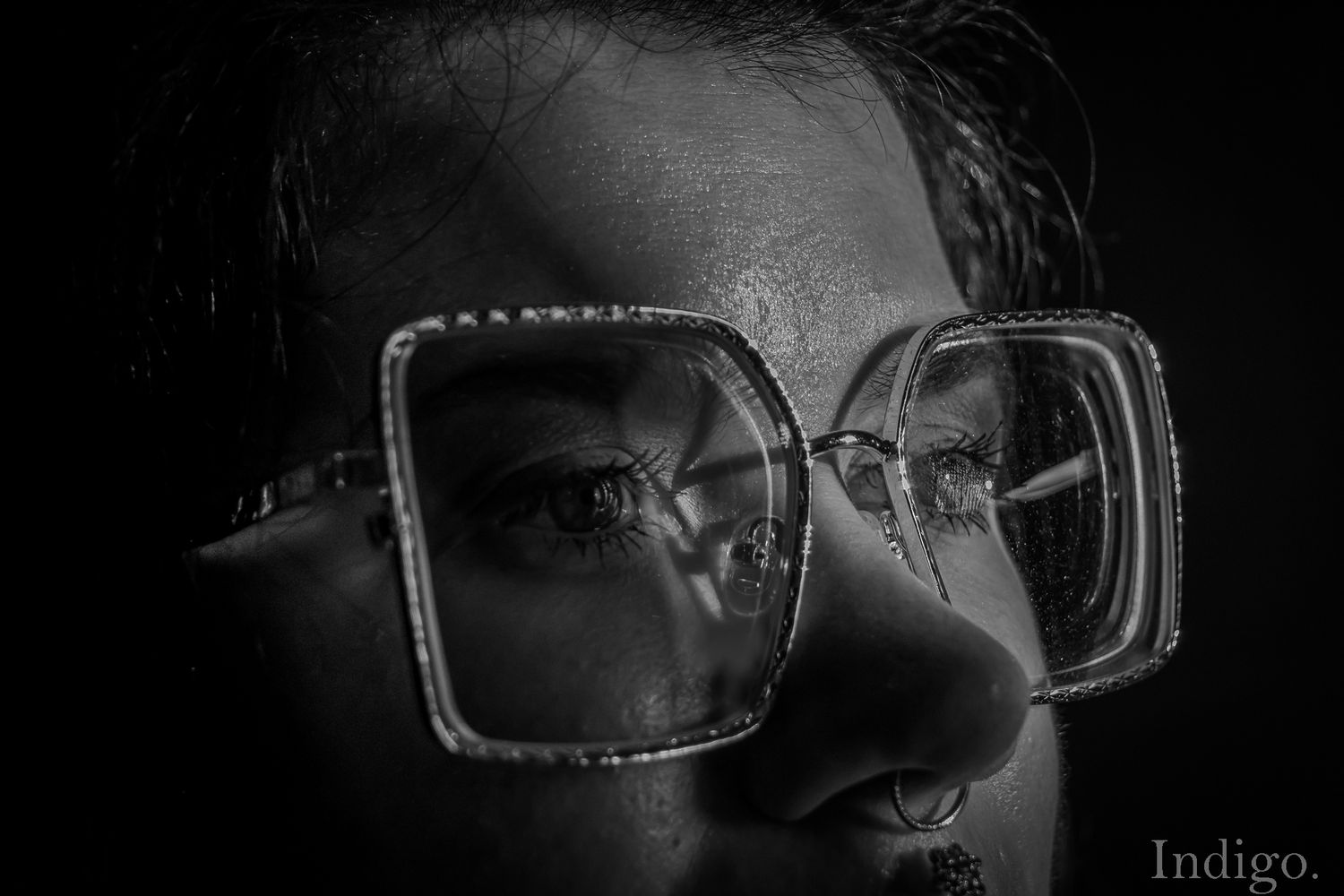 Dramatic black and white close-up of glasses frames in low light.
