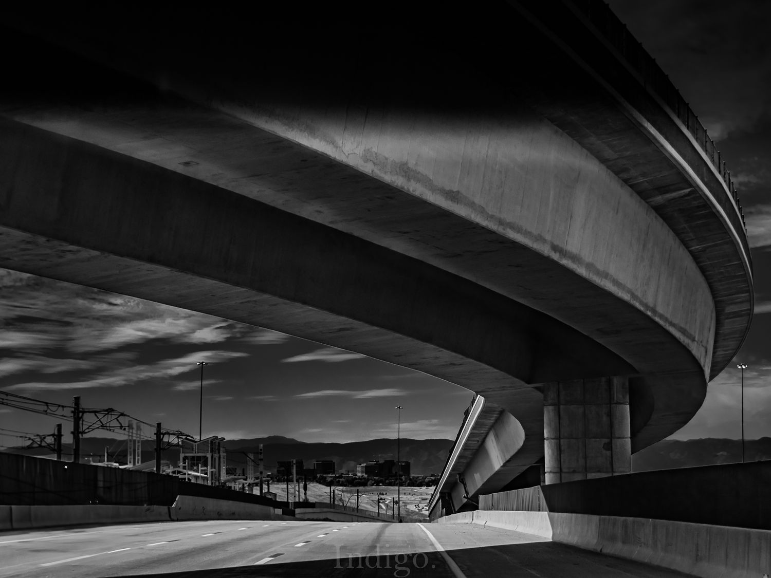 Curved concrete highway overpass structures creating dramatic shadows and lines in black and white.