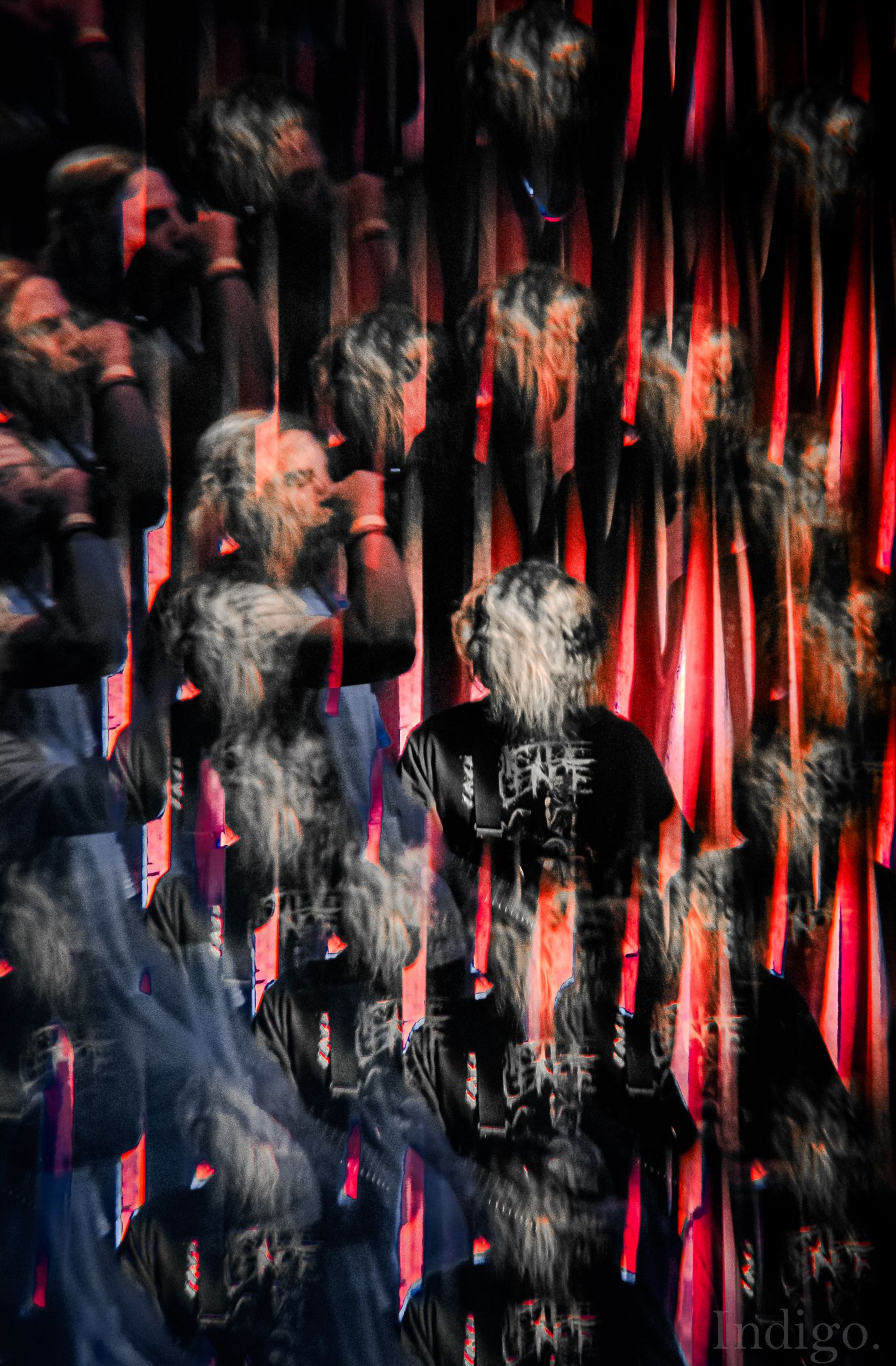 Abstract motion blur of performers on stage with red lighting creating streaks of movement.