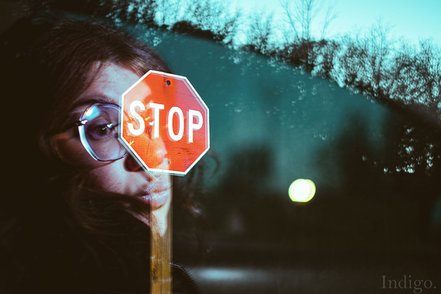 Creative portrait incorporating a stop sign reflection with twilight blue tones.