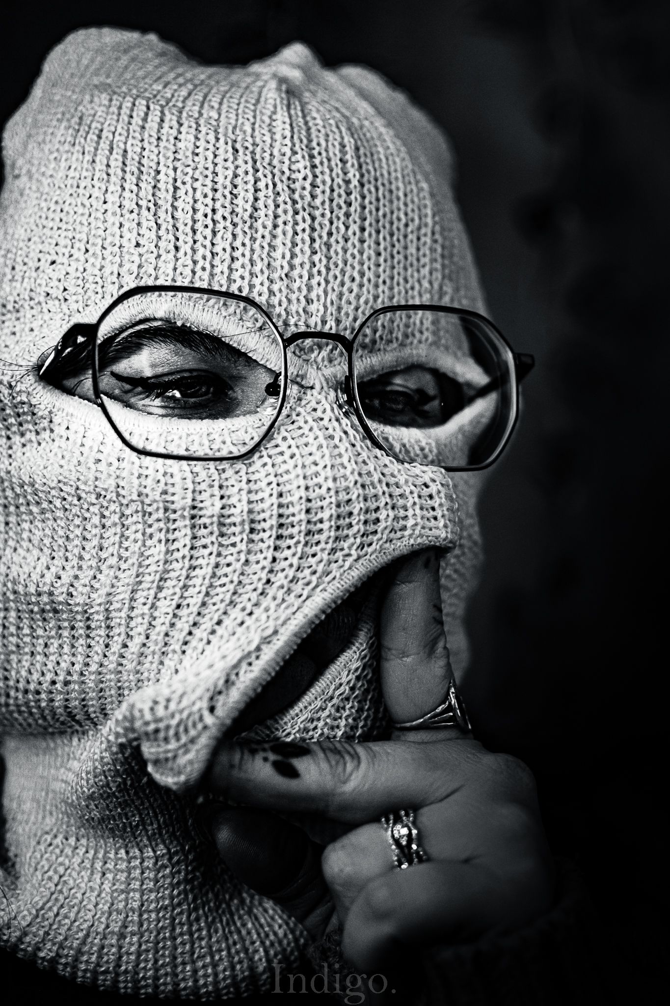 Dramatic black and white close-up shots of someone wearing a white knitted mask and glasses.