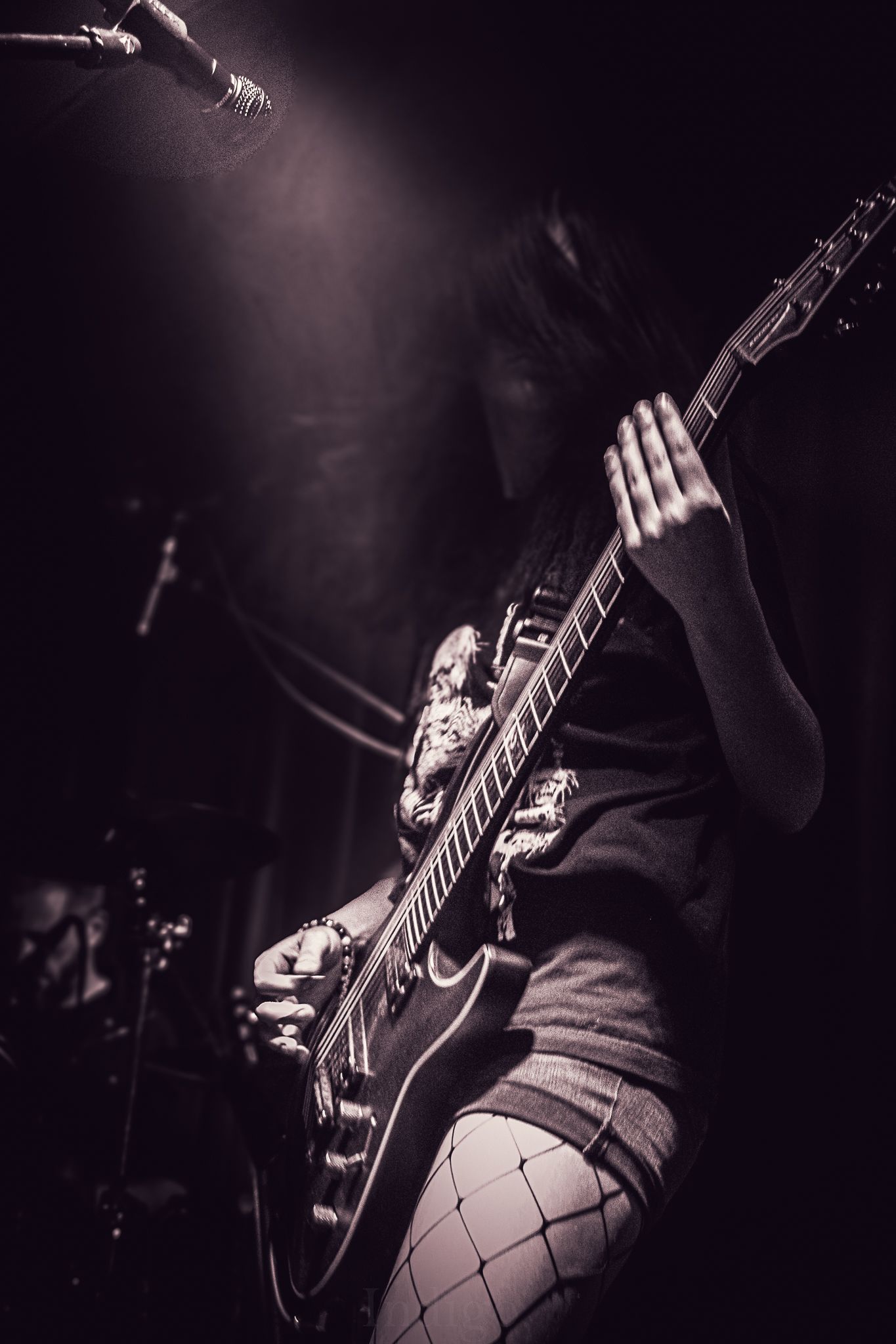 Musician playing electric guitar on stage in black and white.