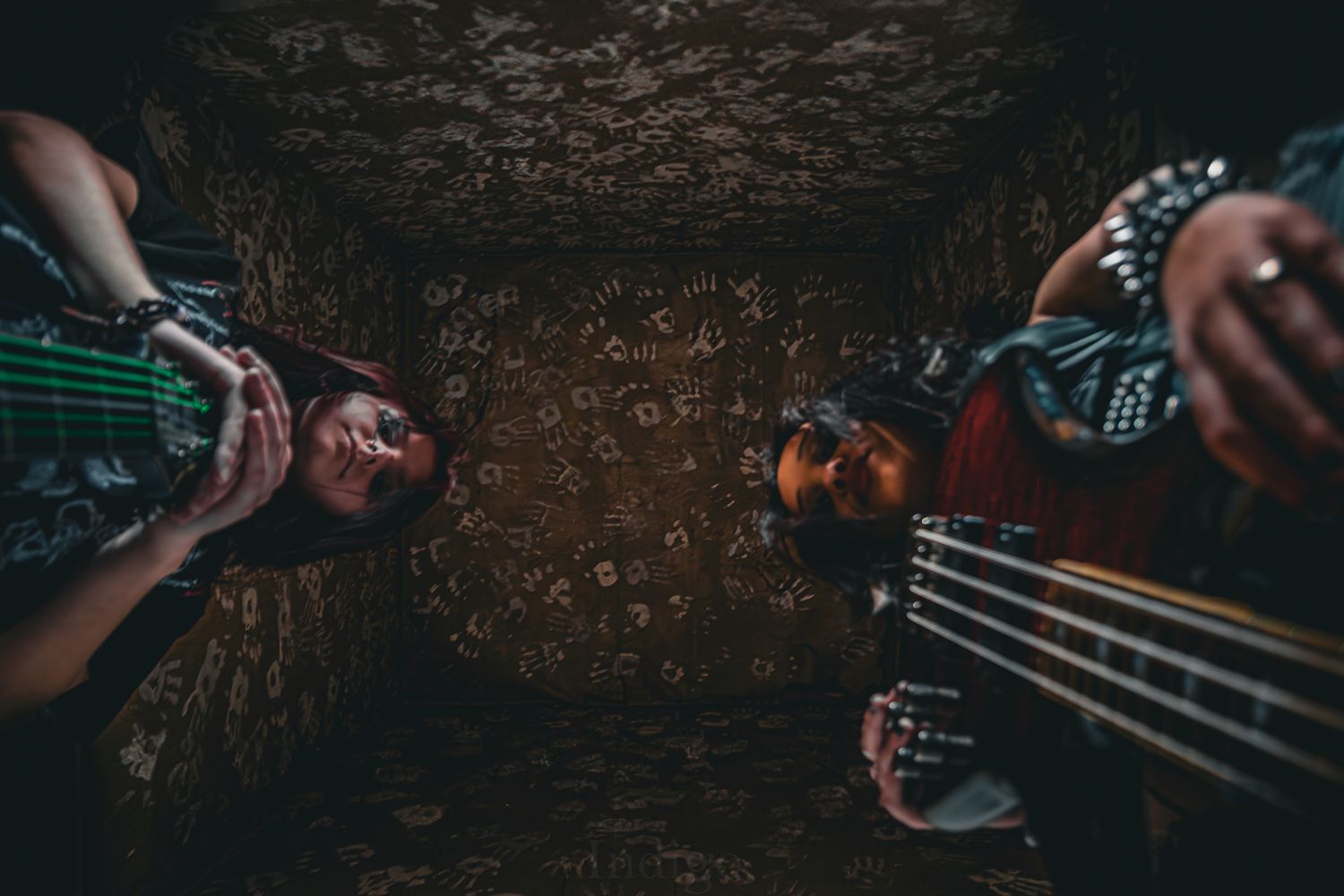 Hands playing guitar strings in dramatic dark lighting.