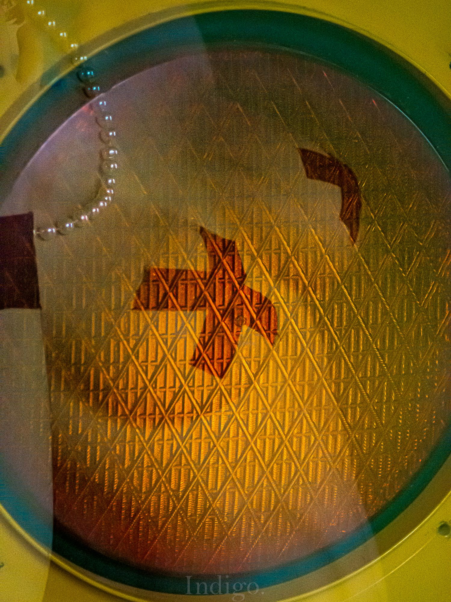 Geometric yellow and green pattern creates an optical illusion with repeating diamond shapes.