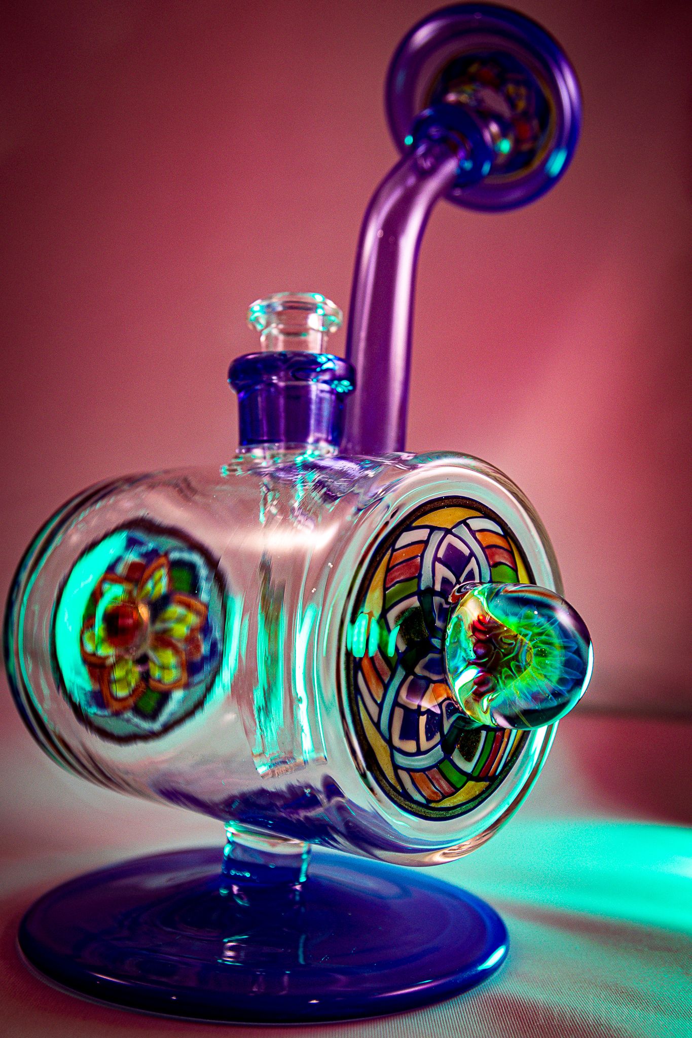 Glass water pipe photographed with vibrant pink and turquoise lighting effects.