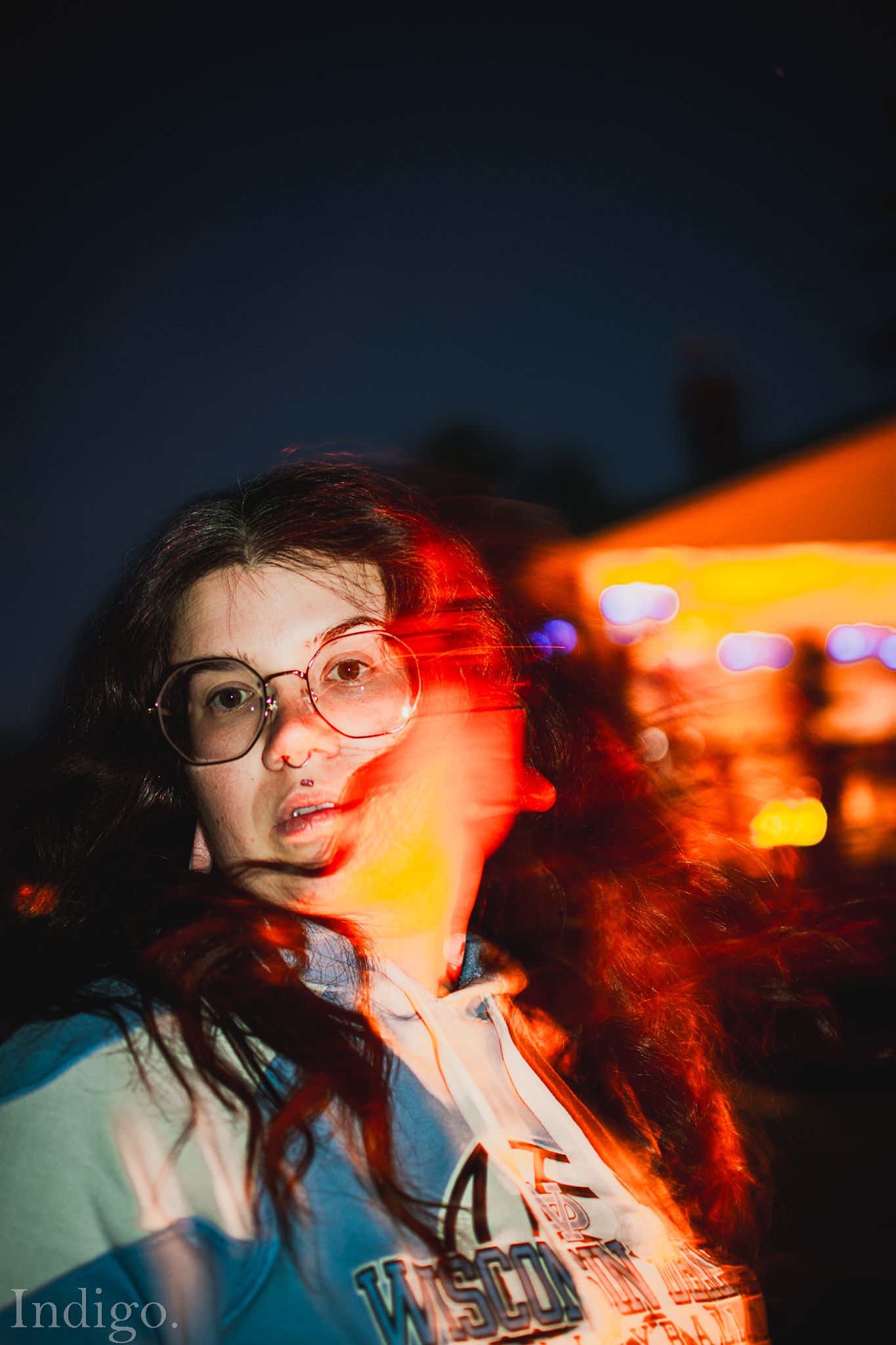 Creative portrait with red lighting and neon bokeh effects in an urban nighttime setting.